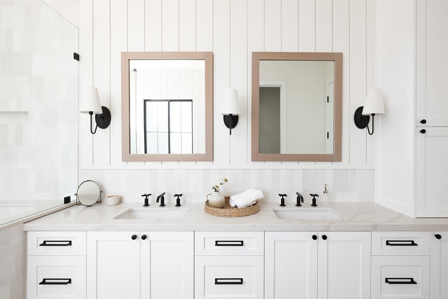 A lot of small details bring this farmhouse bathroom together from the kohler cross faucet handles, shiplap siding, and white oak framed mirrors to the glaze on the ceramic tile giving the shower walls variation.  We love it all.
