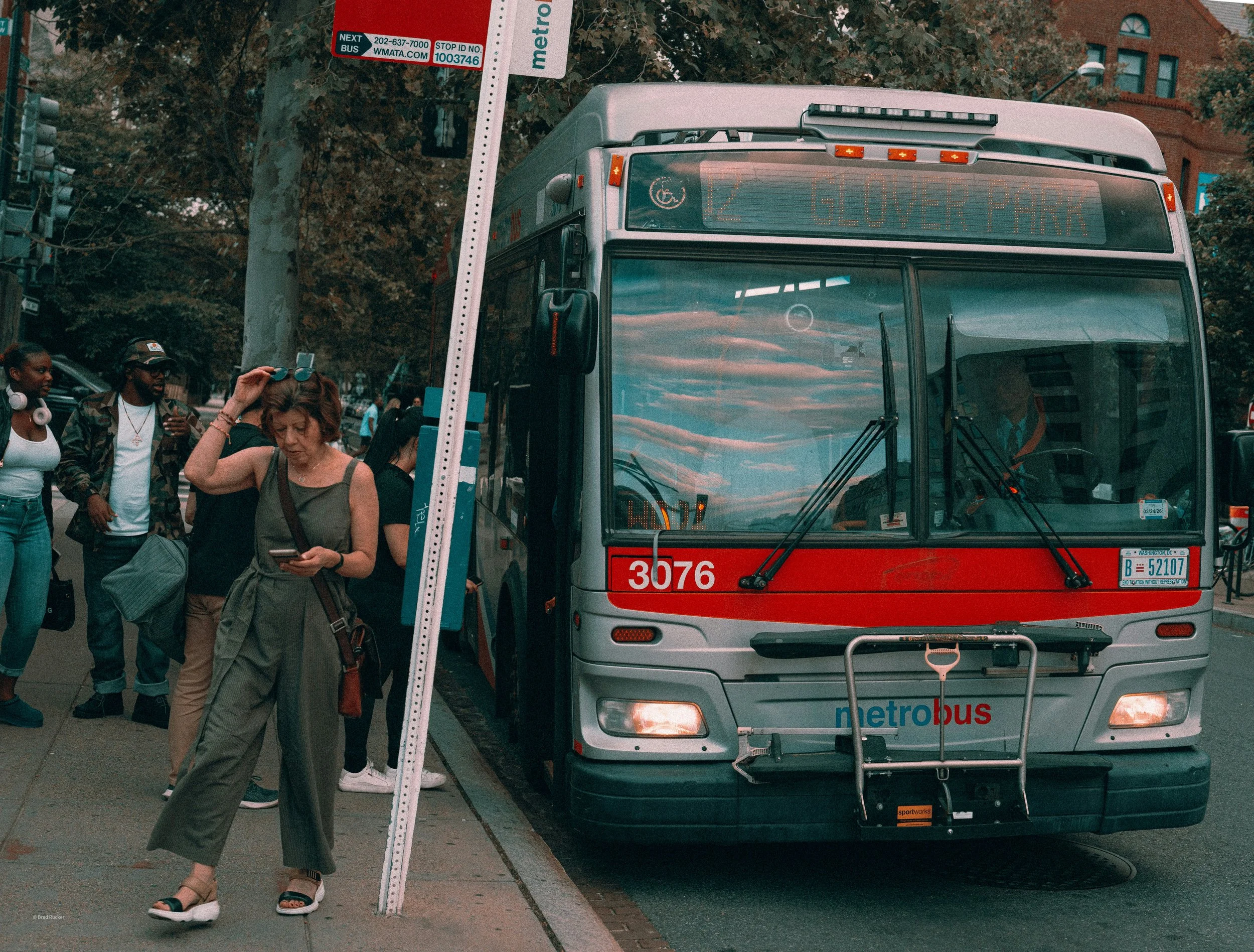 Woman looking at her phone next to a bus
