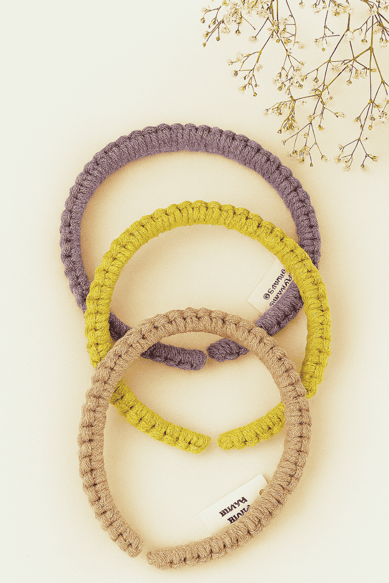 Three handmade macramé headbands in lavender, mustard yellow, and blush pink, styled on a neutral background with dried flowers – Samra Knots boho accessory.