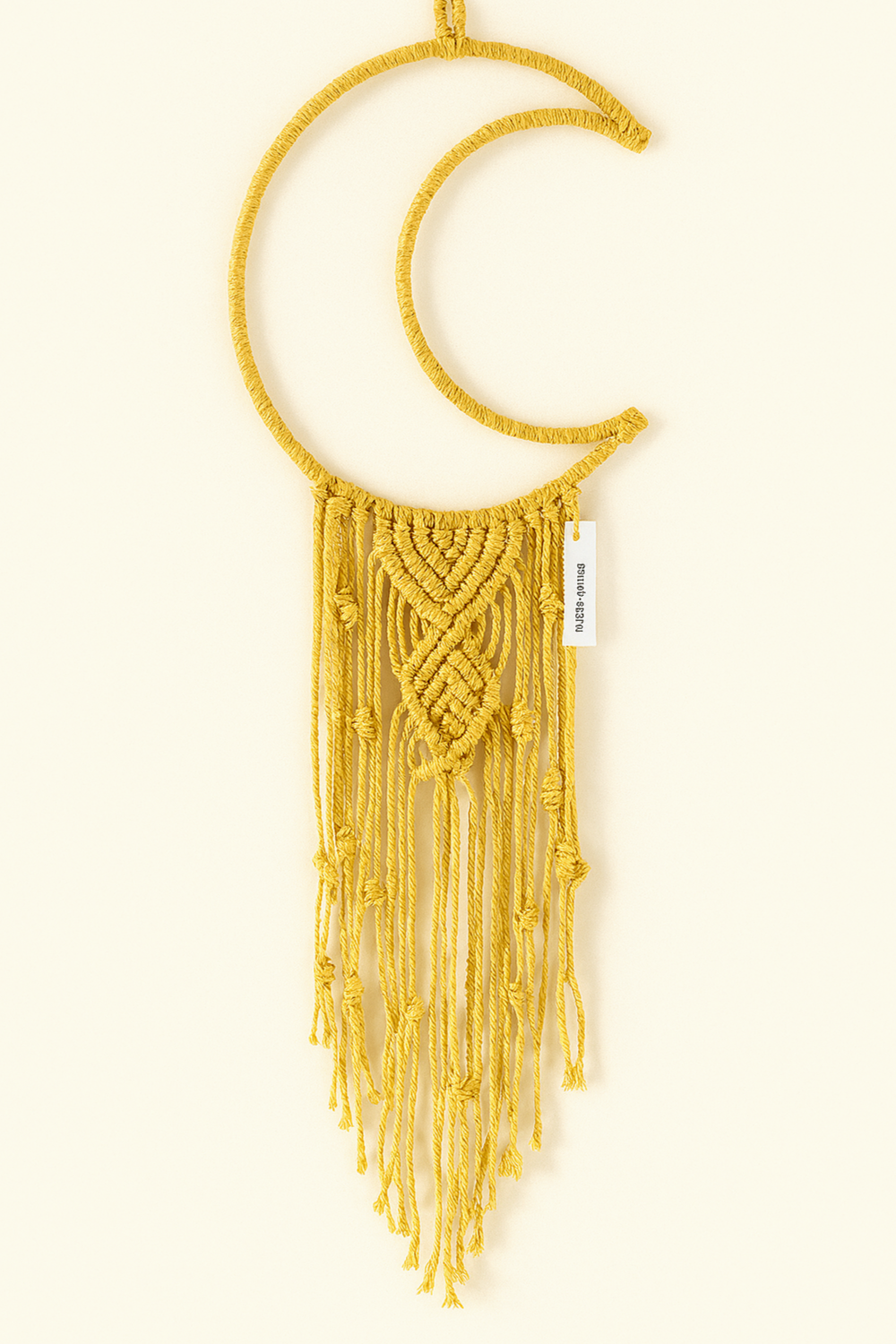 Yellow handmade macramé crescent moon wall hanging with textured twisted knots and long fringe, styled on an off-white background. Bright bohemian home decor.