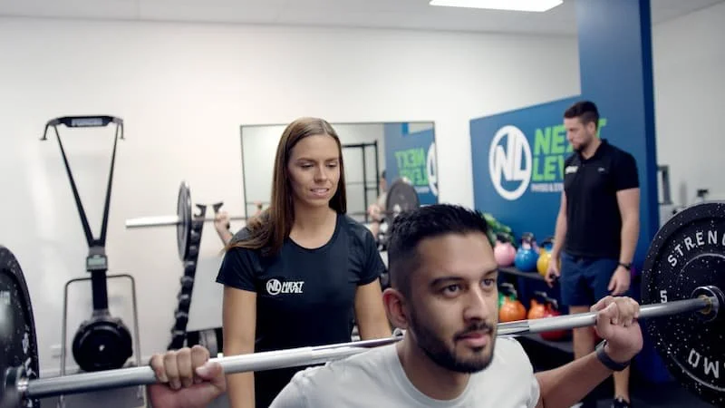 Physiotherapist guiding exercise-based rehabilitation session in Varsity Lakes clinic