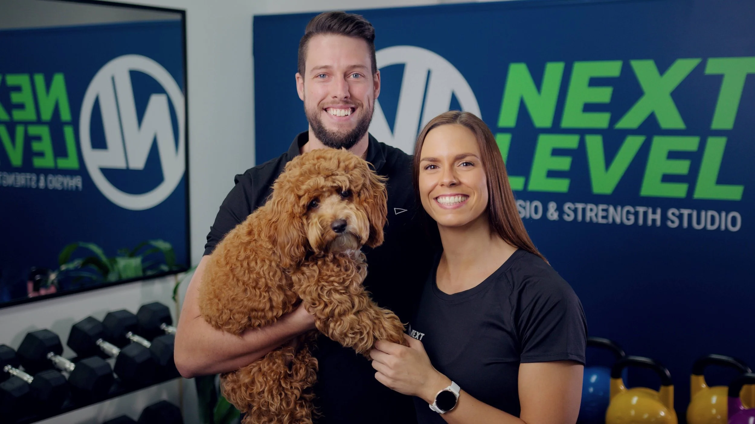 Aleana and Cory Myers outside Next Level Physiotherapy clinic in Varsity Lakes with their dog