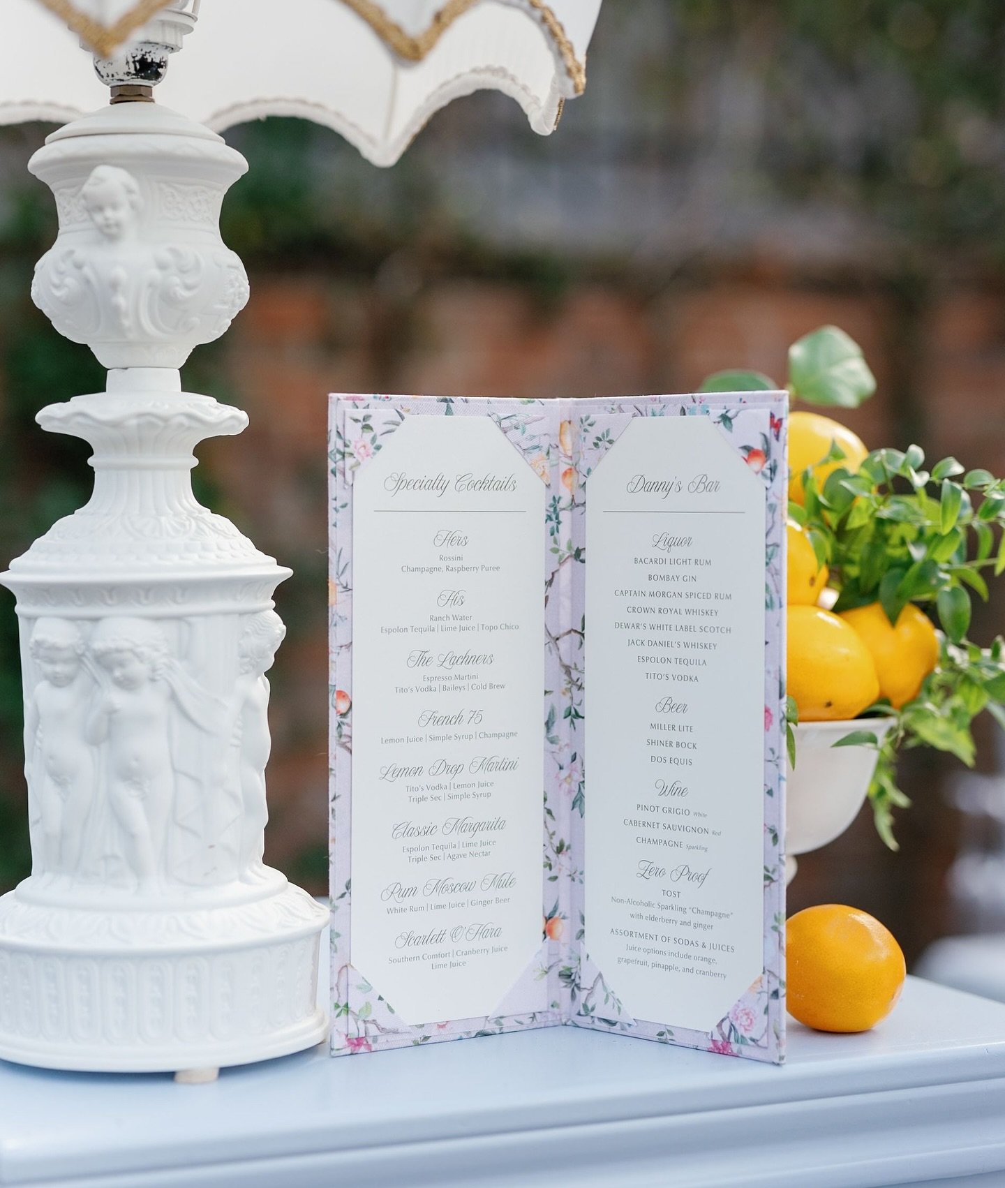 A cocktail experience designed to delight &mdash; this fabric-wrapped bar menu brought a refined, restaurant-style touch to the celebration. Adorned with a custom pattern inspired by the garden setting such as botanicals, citrus, birds, and butterfli