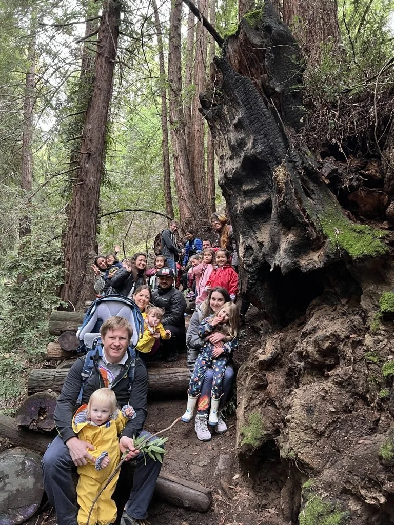 Families posing among redwoods beside a charred redwood trunk in the East Bay.