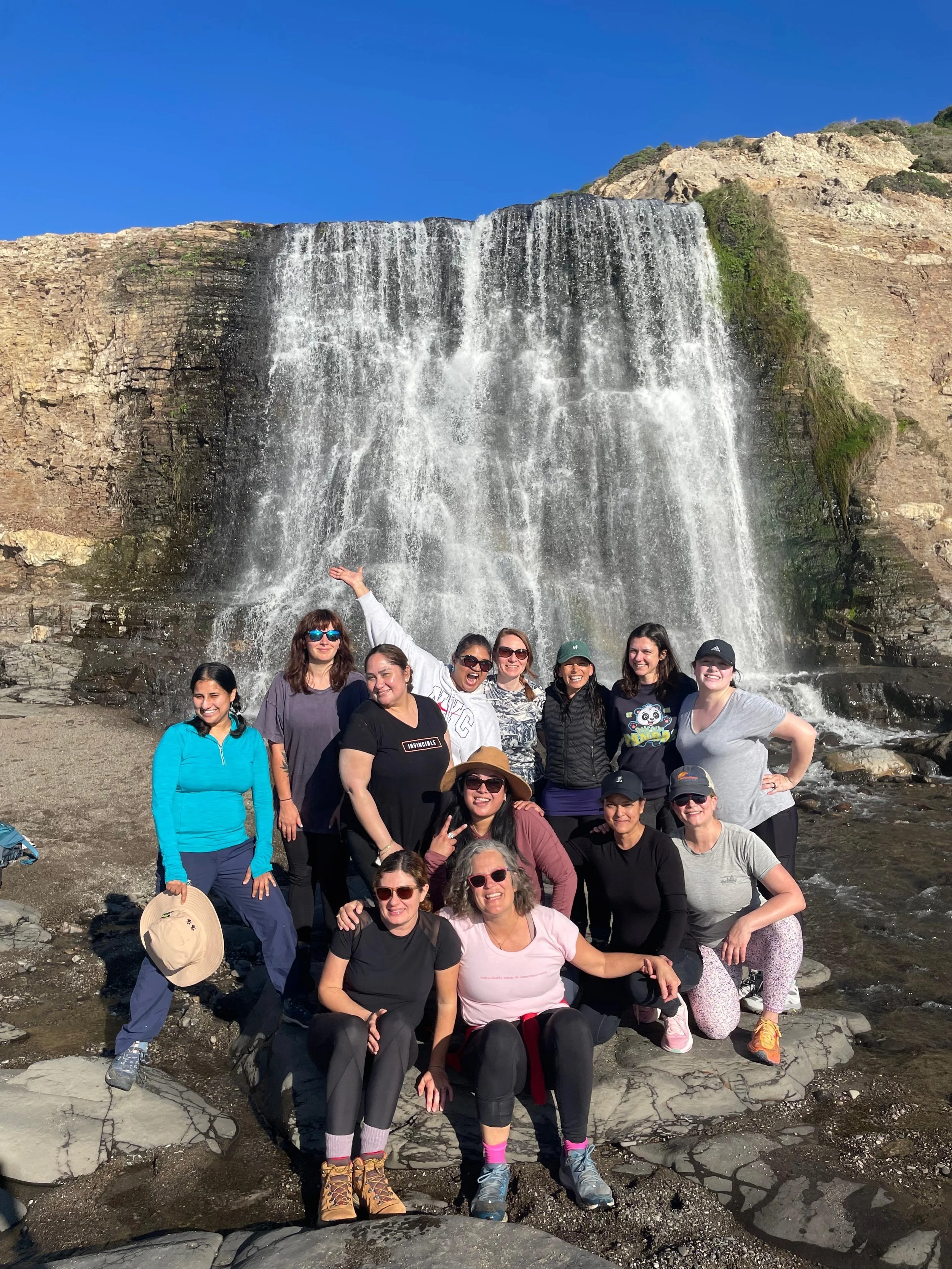 A group of women posing in front of Alamere Falls at Point Reyes.
