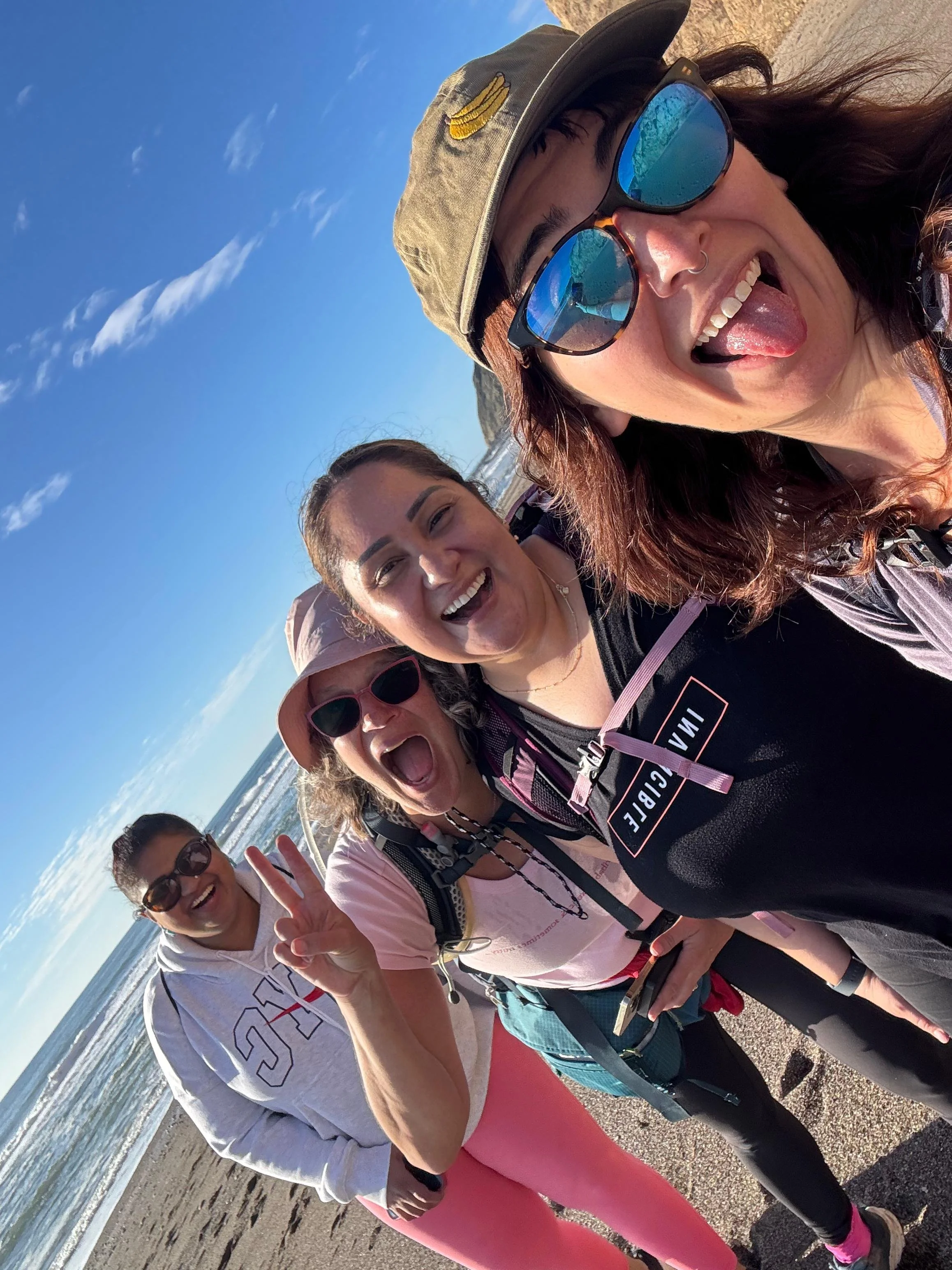 A group of women taking a laughing selfie on the beach at Point Reyes.