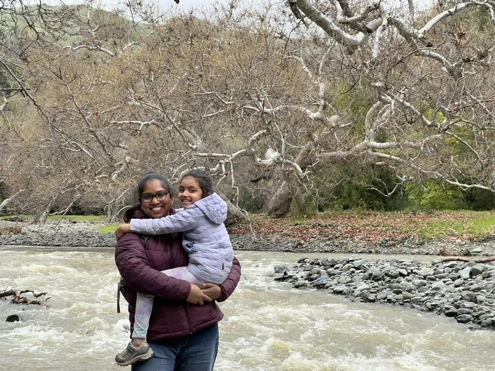 A parent holding a child beside a rushing creek at Little Yosemite in the East Bay.