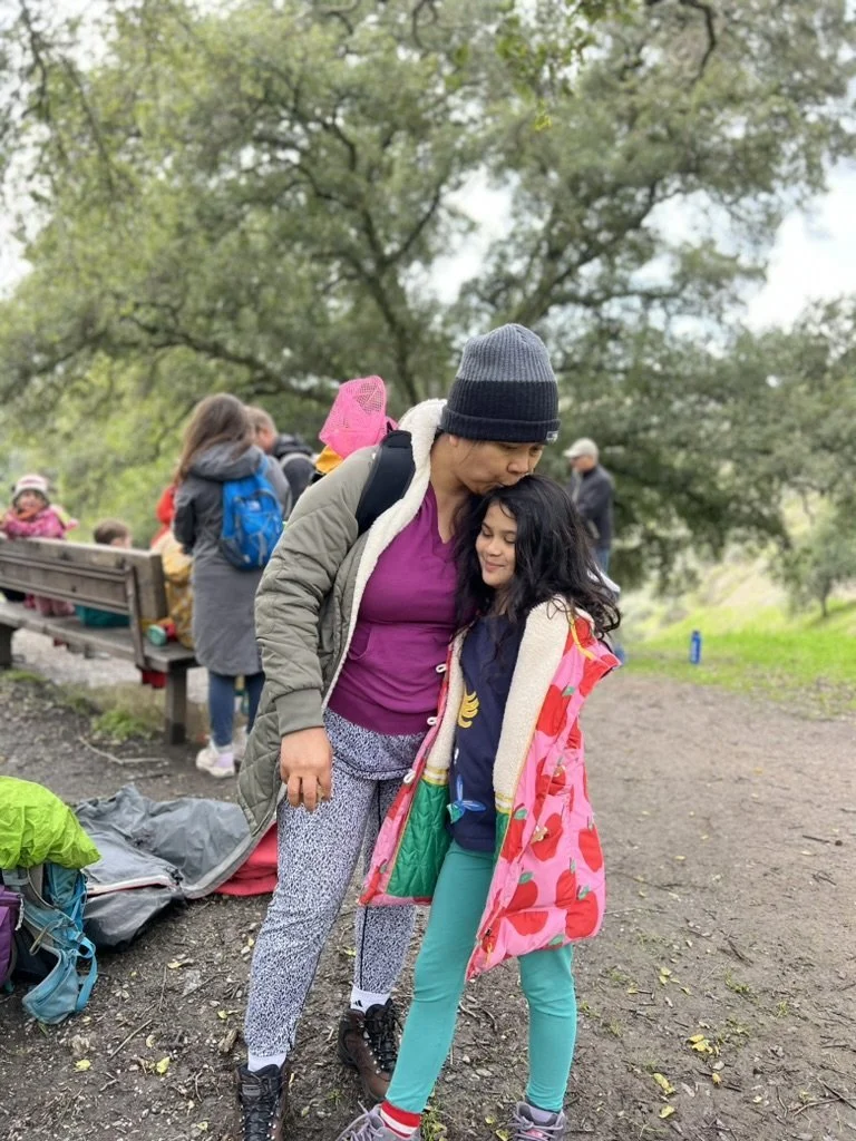 A parent hugging a child on a trail beside picnic benches at Little Yosemite in the East Bay.