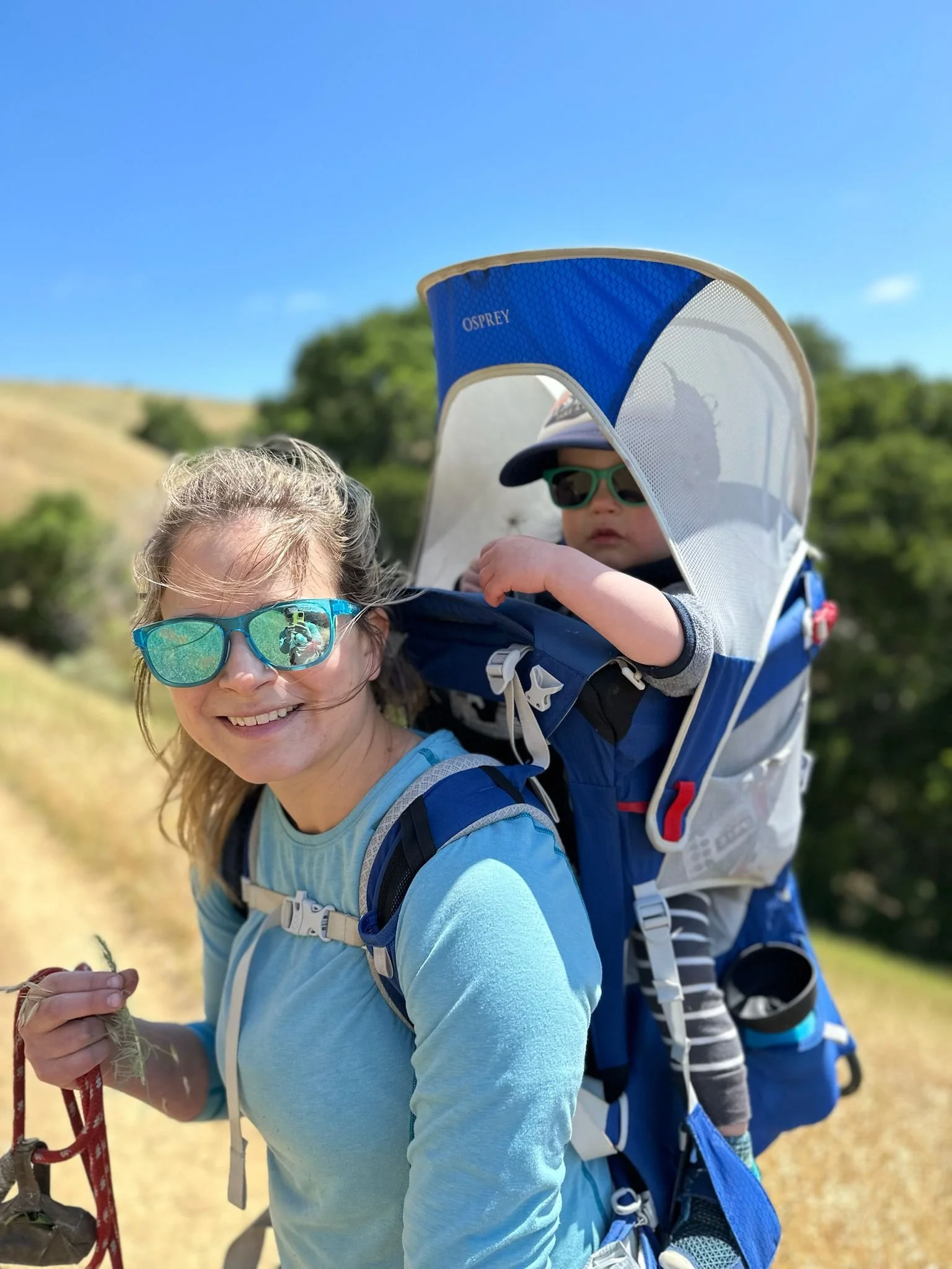 Sarah Wilson, Family Adventure Squad guide, hiking golden California hills with her child in a backpack carrier