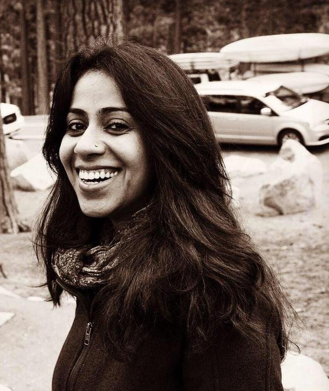 Sepia portrait of Sneha Mahecha, Family Adventure Squad writer, smiling among tall pine trees