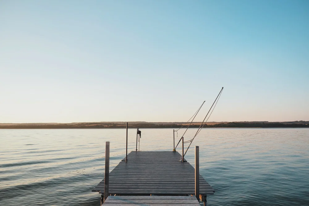 A wooden dock extending into a calm lake at sunrise