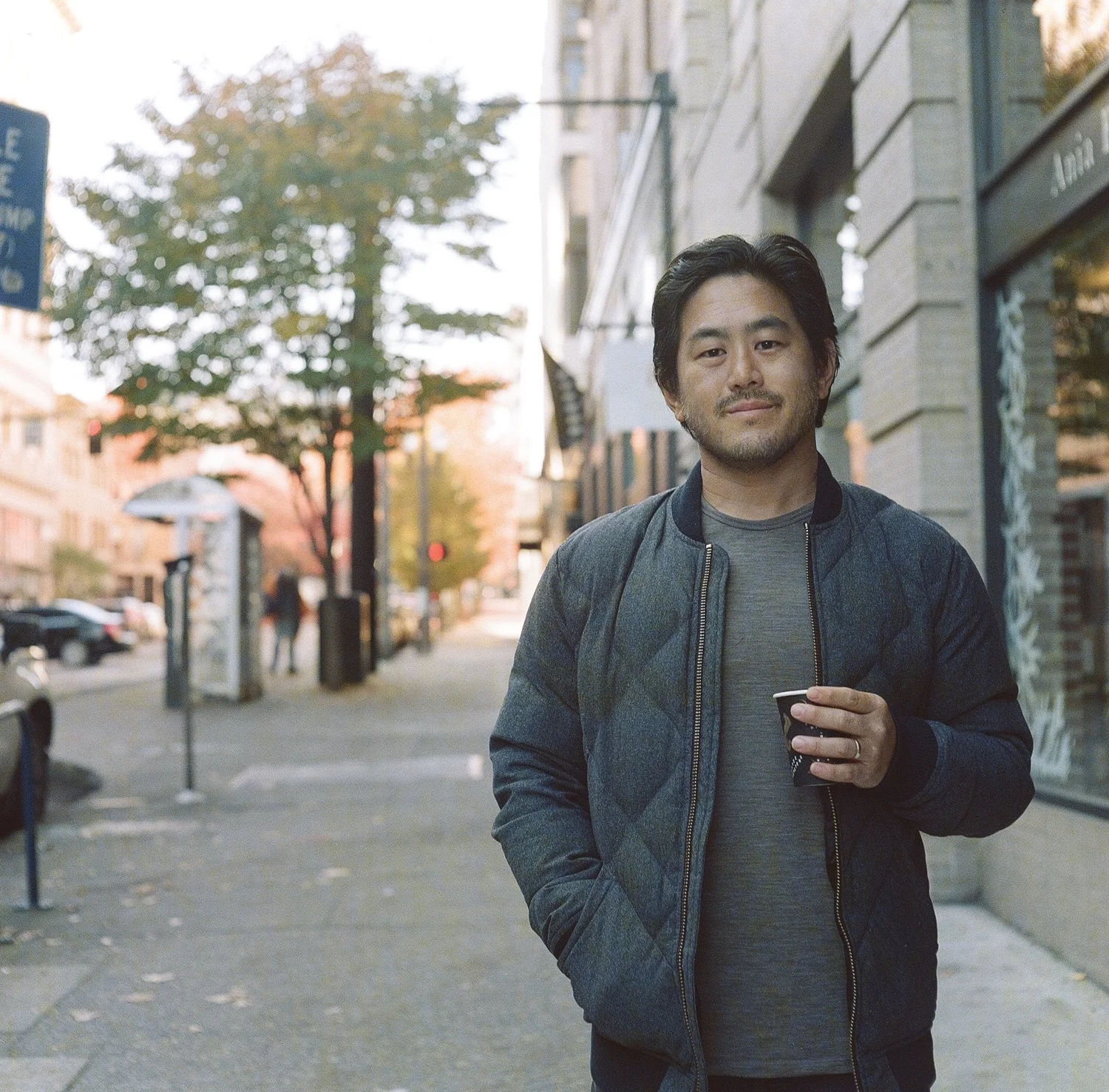 Gene Lee on a Portland sidewalk, coffee in hand
