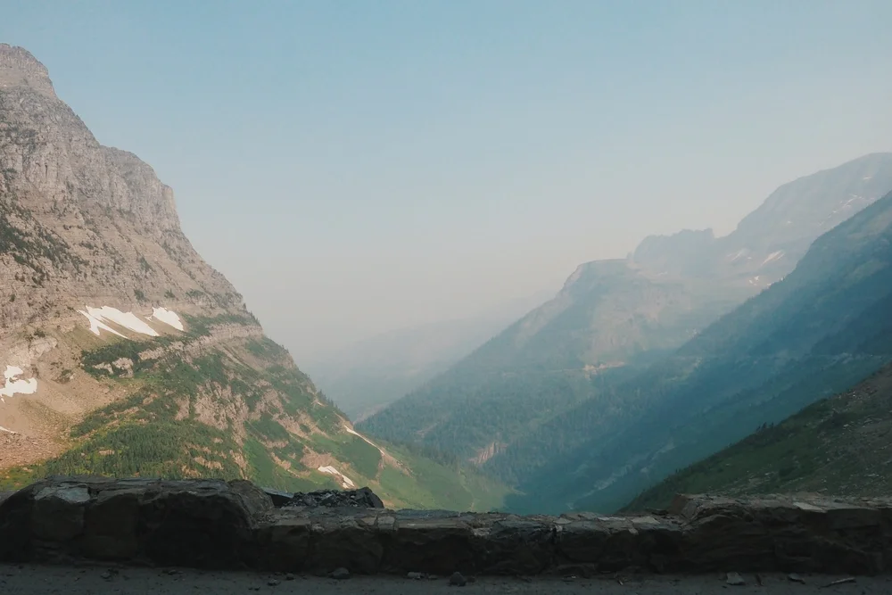 Mountains rising over a valley with a stone wall in the foreground