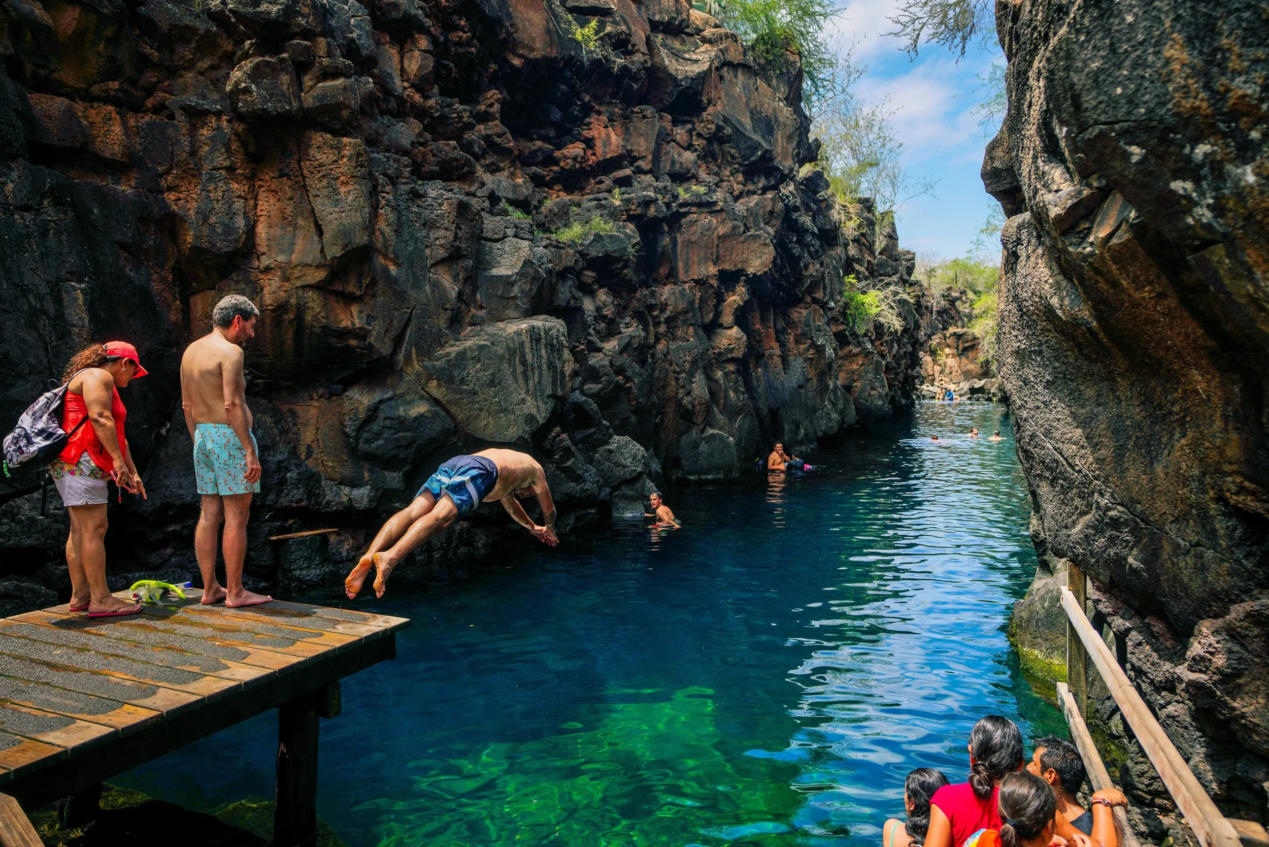 People swimming and jumping into a natural water pool in Las Grietas Galapagos.