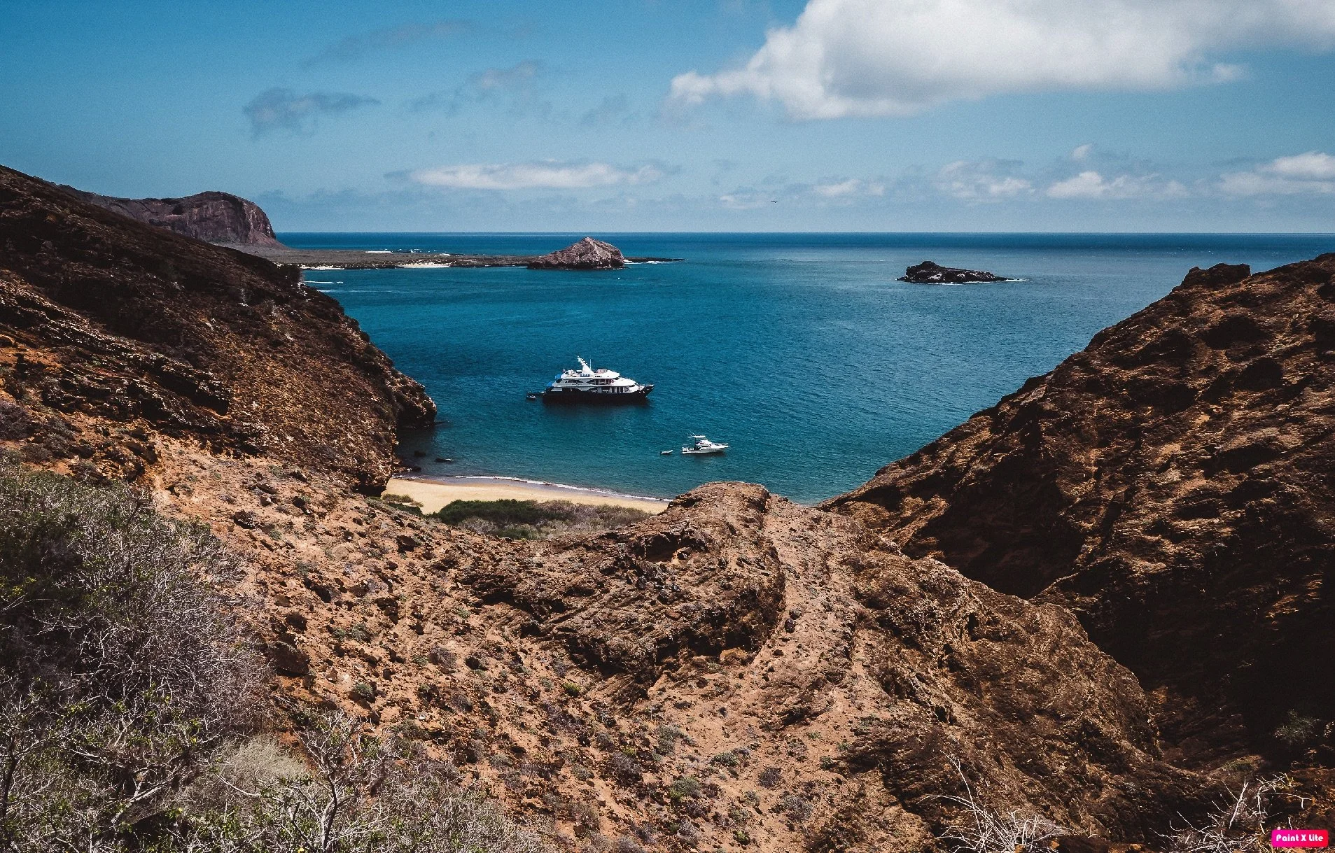 View of a bay with boats, surrounded by rocky cliffs and hills in punta pitt san cristobal, Galapagos..