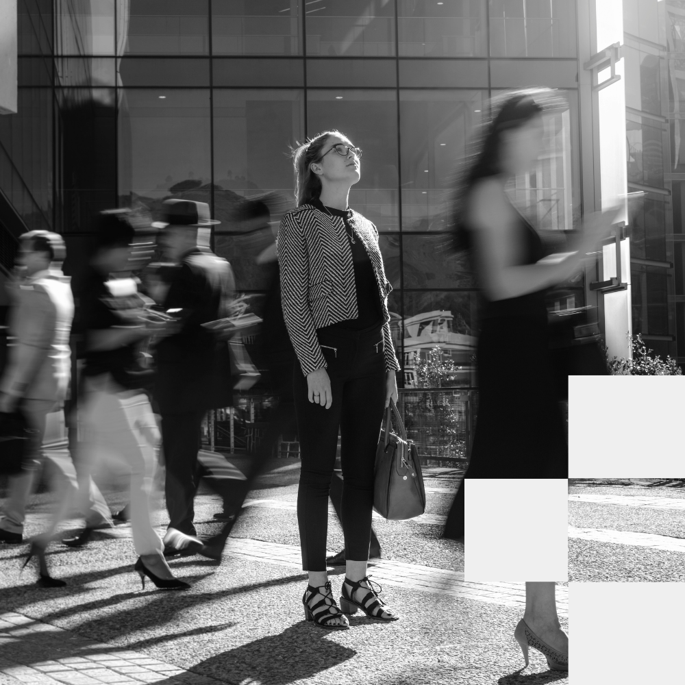 Professional woman standing in urban environment with pedestrians and glass buildings