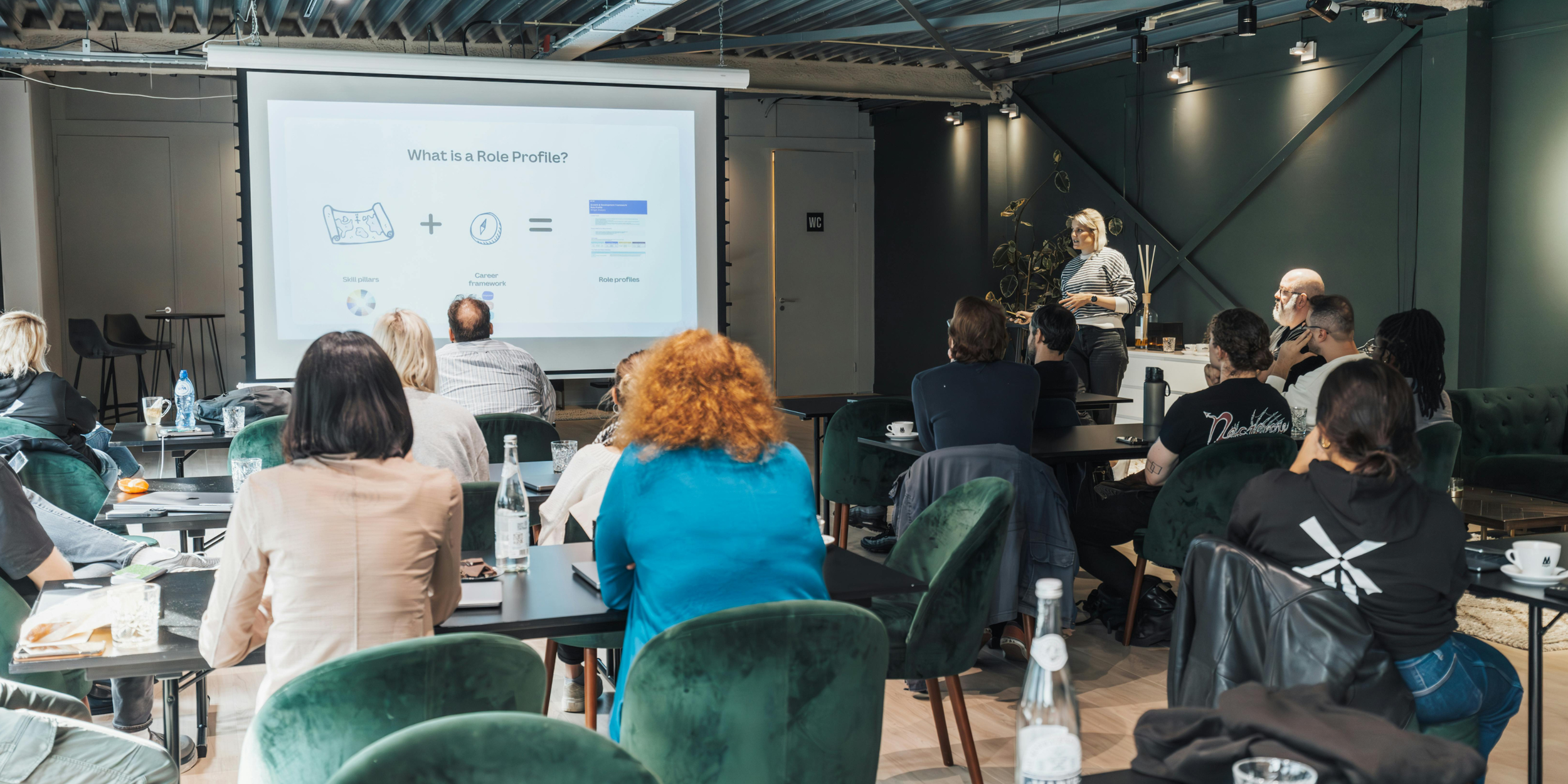 People in a training session sitting looking at a presentation with a trainer to one side.