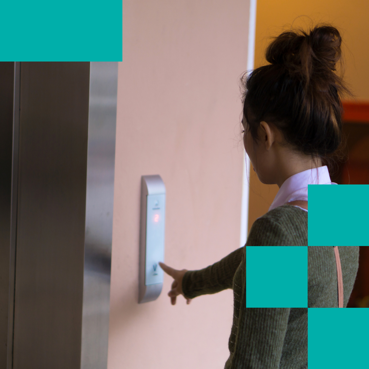 Professional woman with dark hair in messy bun pressing elevator button