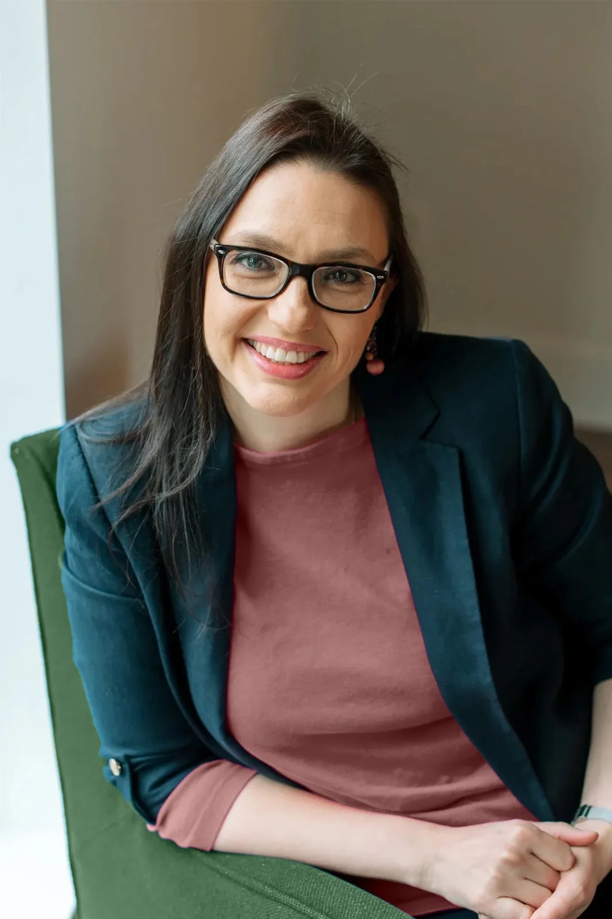 Smiling relationship counselor in virginia with brown hair and glasses wearing a coral top