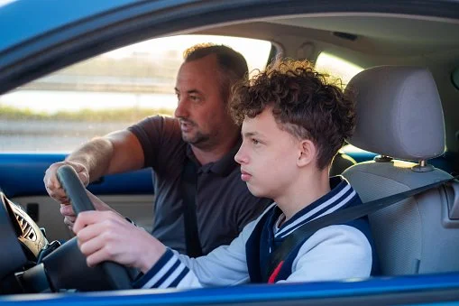 Teenager learning to drive with parent/adult giving help