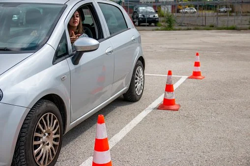 Teenager practicing driving car near cones