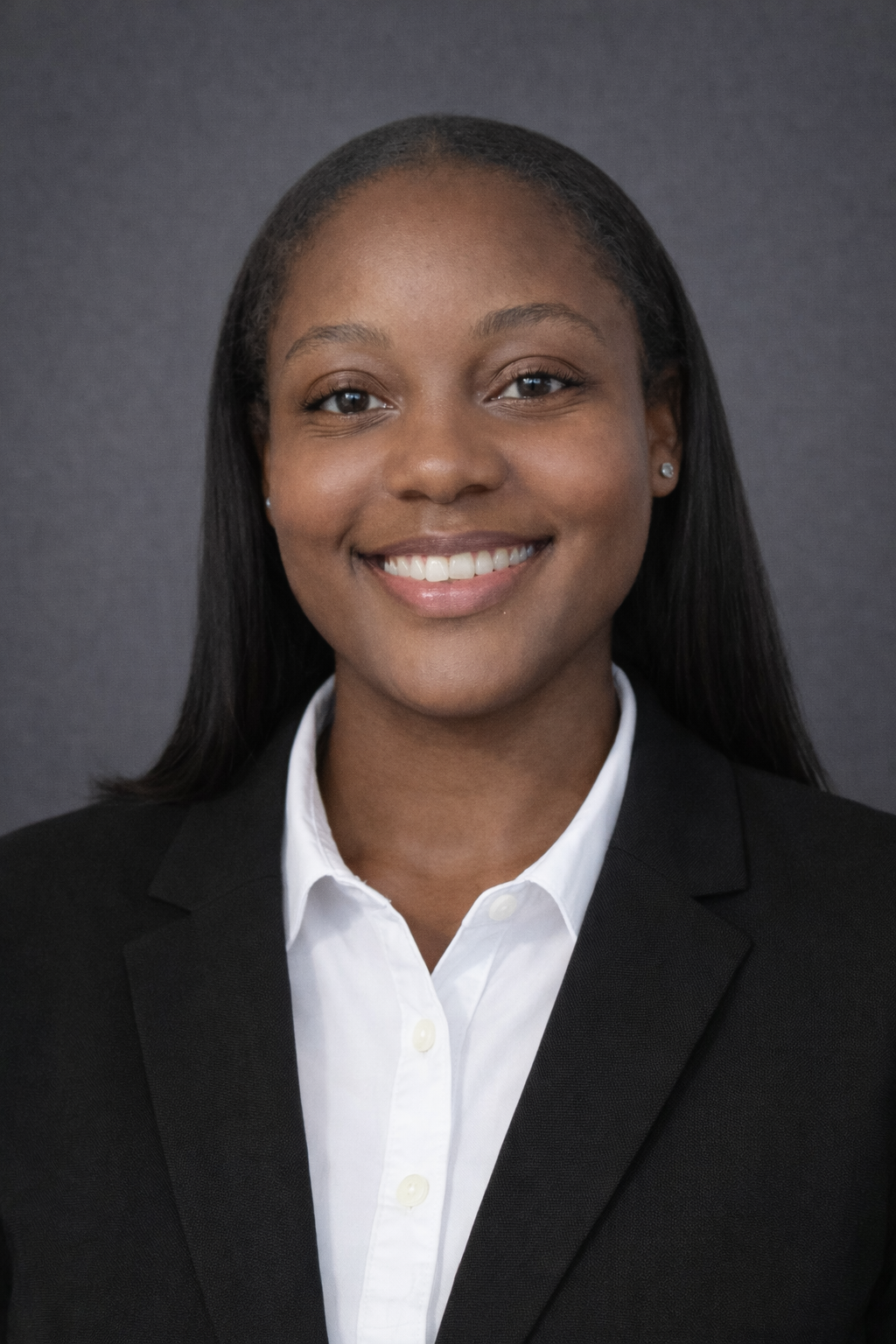 A professional woman smiling, wearing a black blazer and white shirt, against a dark background.
