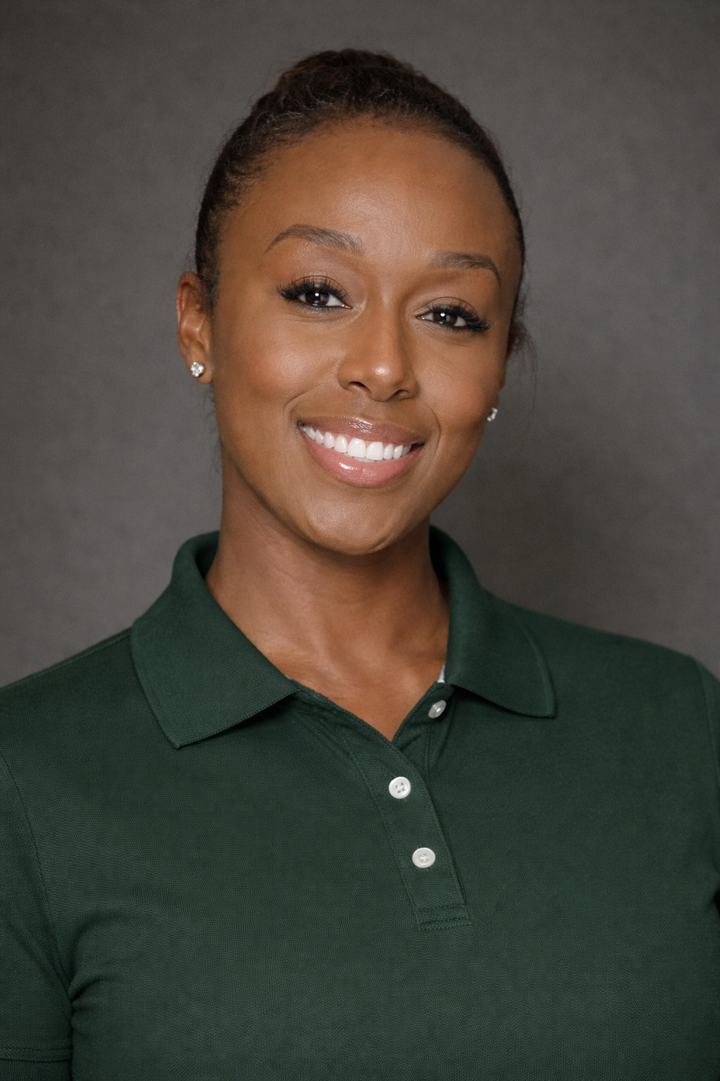 A woman taking a selfie outdoors under a bright blue sky with white clouds, wearing a blue baseball cap, a gray puffer vest, and orange nail polish.
