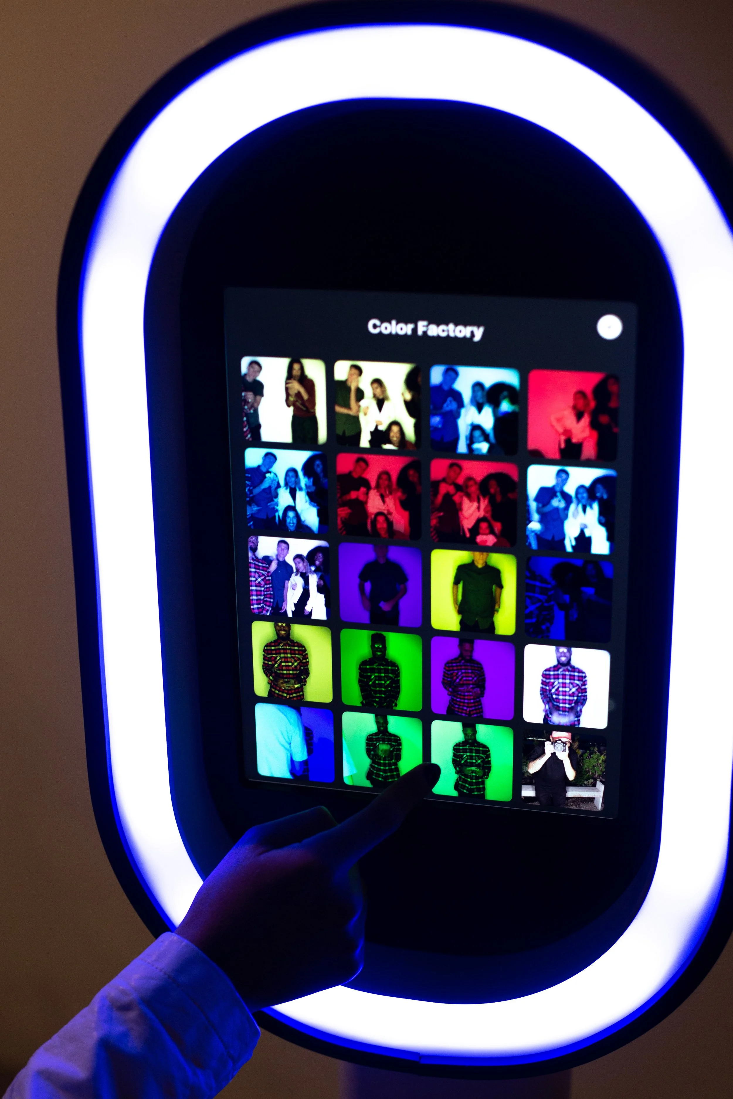 Clt Photo Booth Magik's Selfie booth showcasing the Live photo booth Gallery feature. A hand is touching the screen, navigating through various images framed by a circular LED-lit frame.