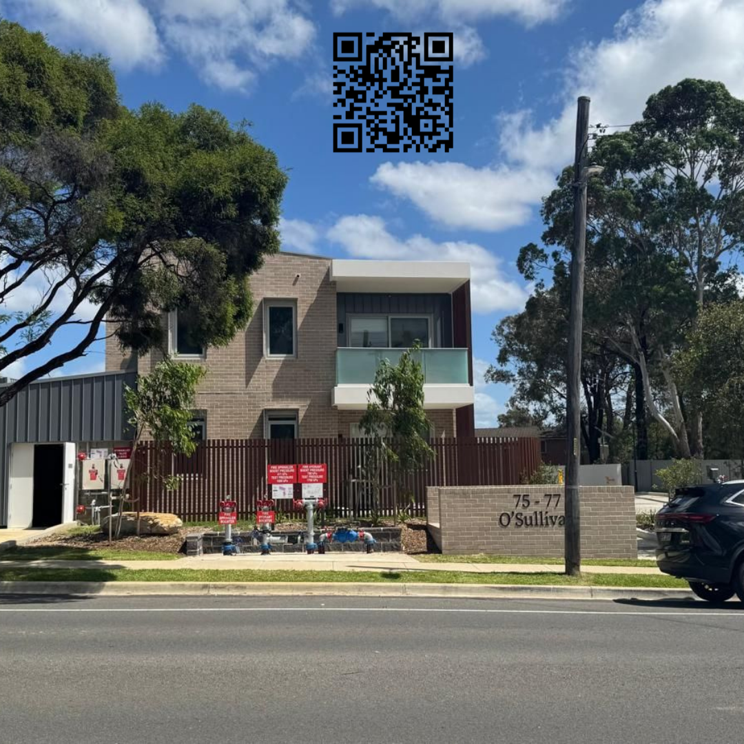 New modern residential building complex with parking area, trees, and a sidewalk on a sunny day.