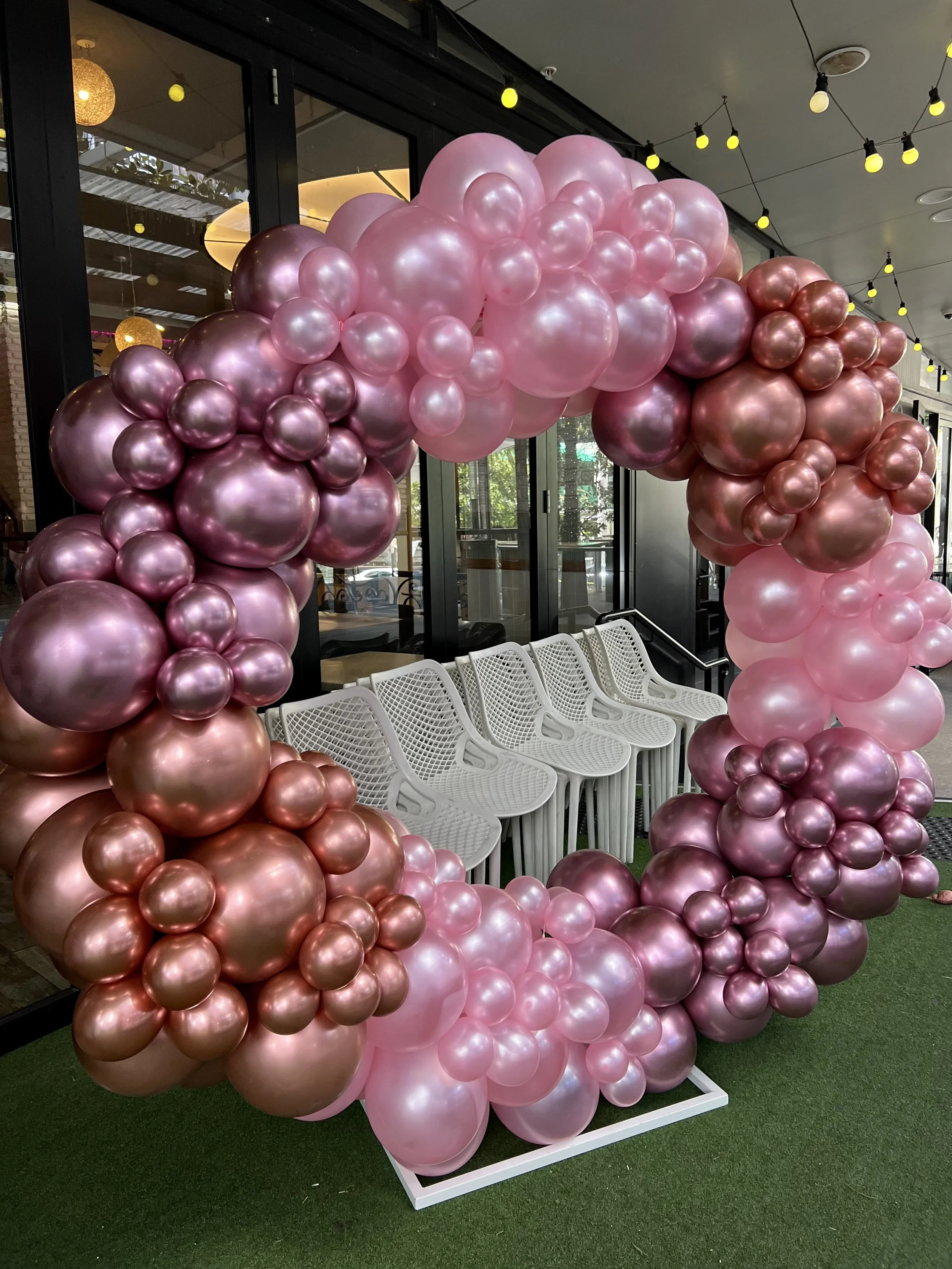 Pink, gold, and mauve balloons garland arranged on a circular arch, a perfect backdrop for a celebration.