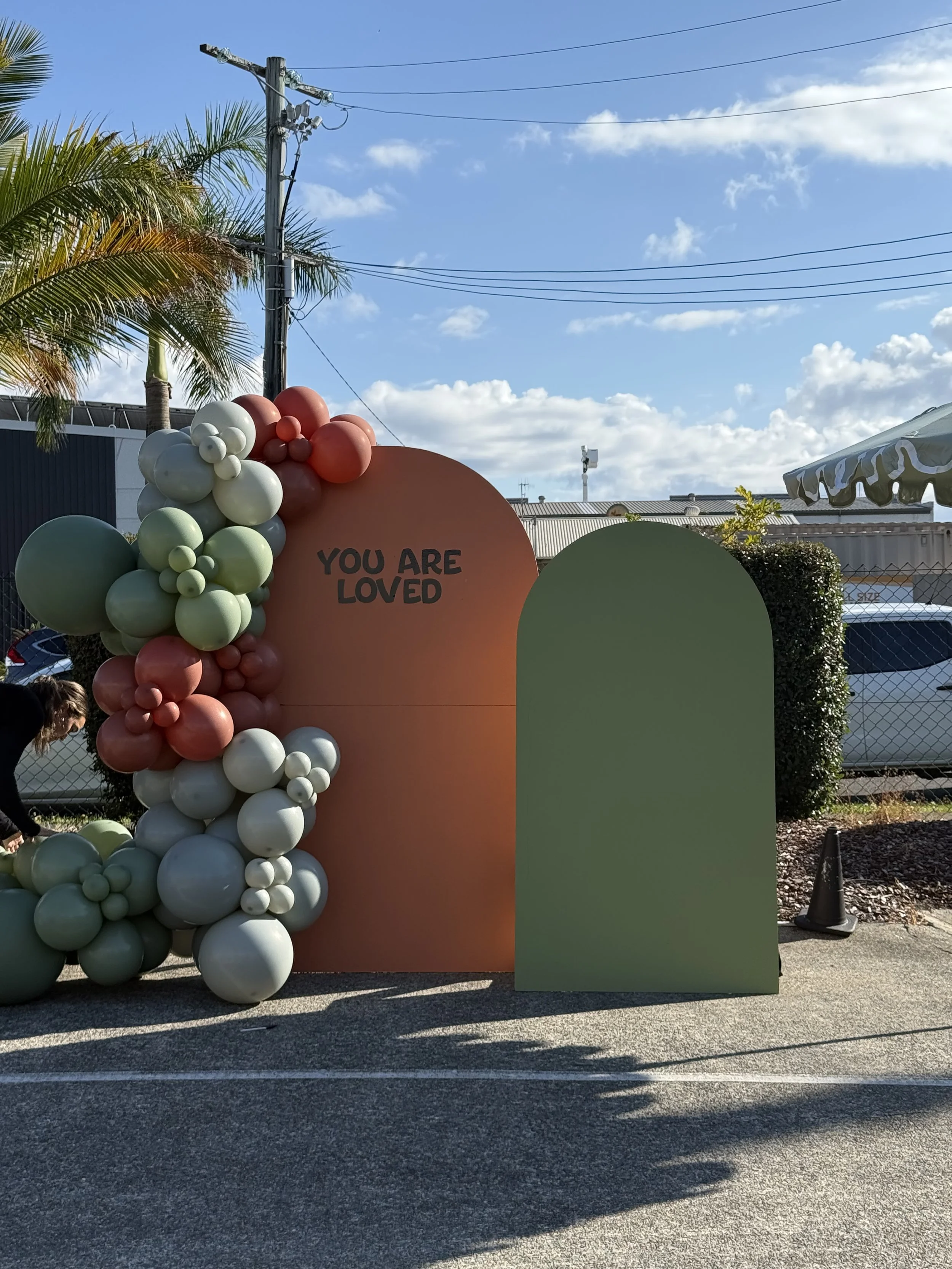 Double arch back drop with a mix of greens and burnt oranges creating a balloon garland.