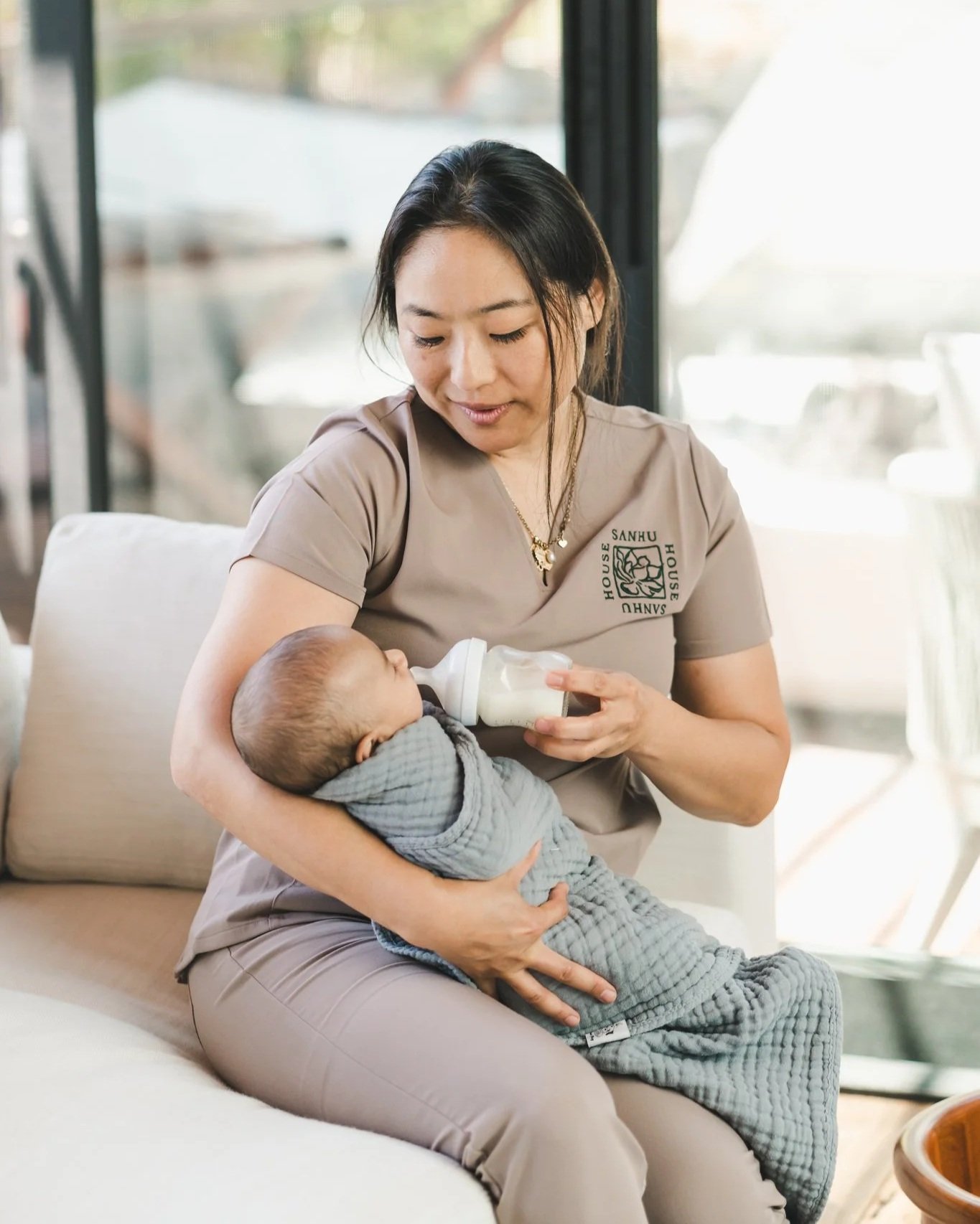 Sanhu House doula bottle-feeding a newborn during daytime postpartum care