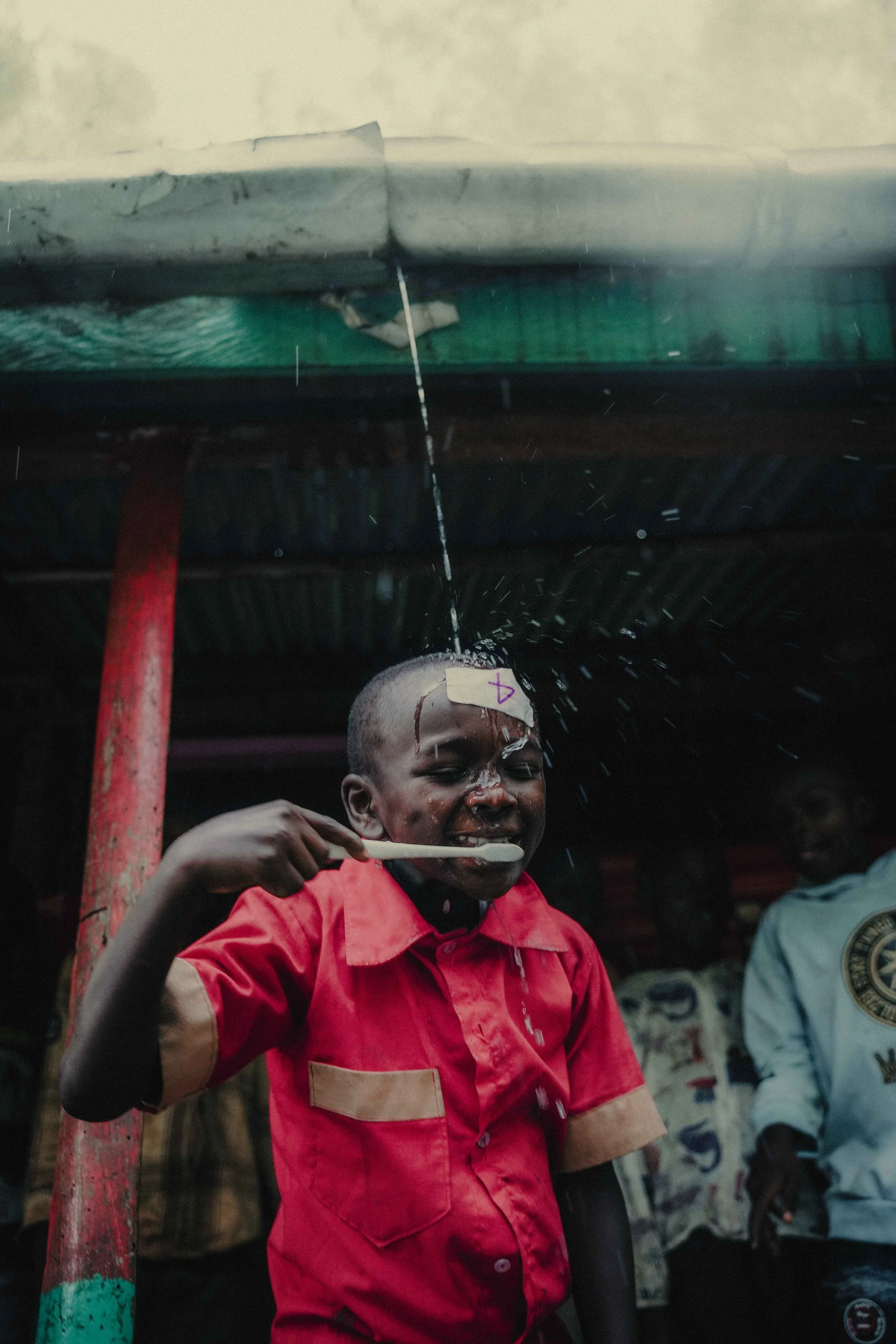 boy brushing teeth gutter water Kenya