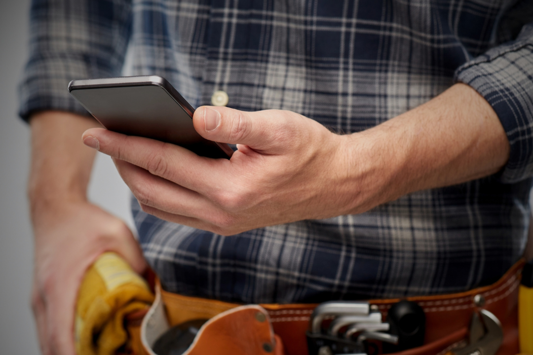 Tradie on a mobile phone managing client calls on site, representing phone answering service and admin support for tradies in Australia
