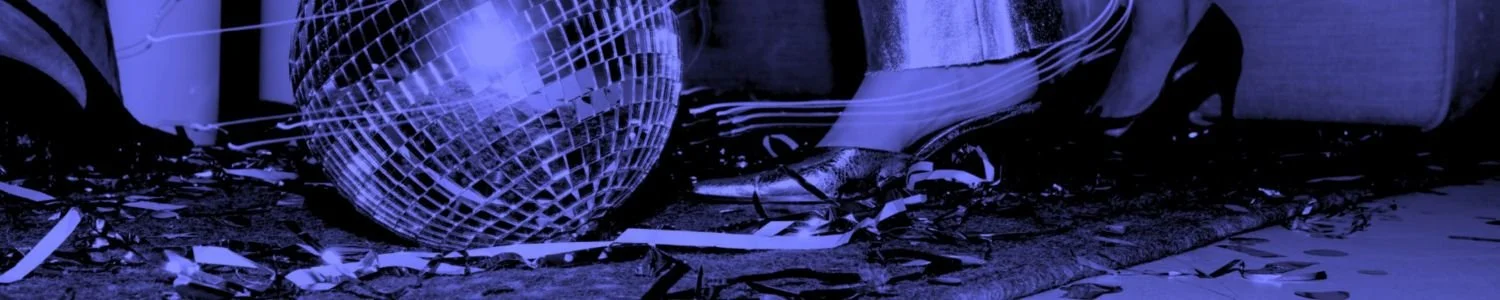 Close-up editorial image of a disco ball, metallic heels and scattered party streamers on the floor in warm monochrome lighting, used as the Assembl Studio website footer image.