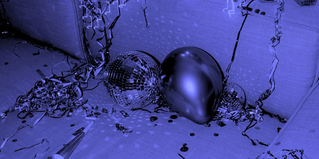 Disco balls, balloons and metallic streamers left scattered after a party in a dimly lit interior space.