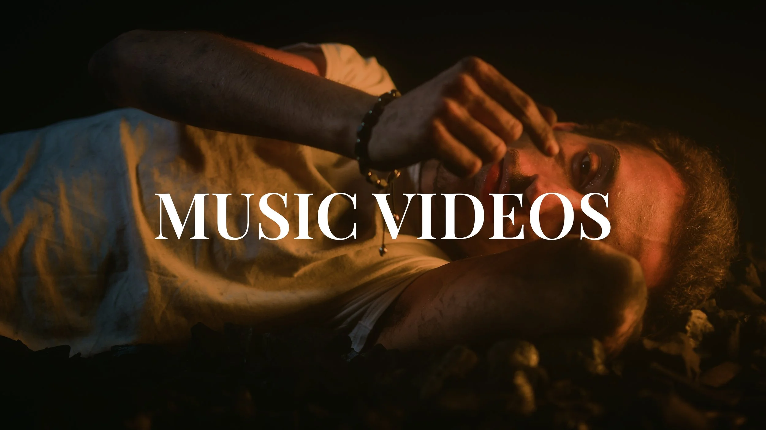 Person lying on the ground with hand near face, with overlaid text 'MUSIC VIDEOS'.