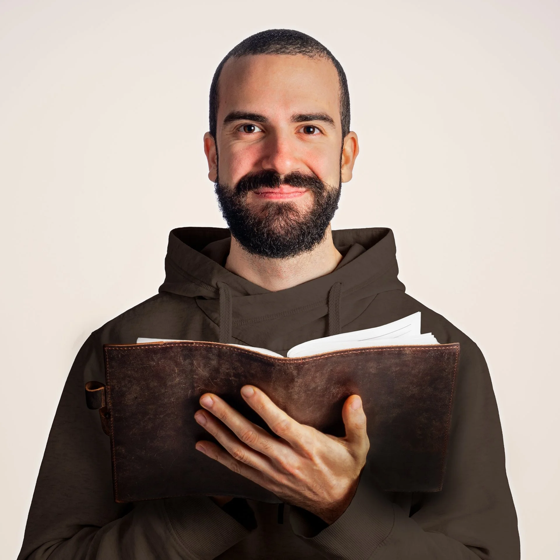 Man with a beard and mustache holding an open notebook and smiling at the camera.