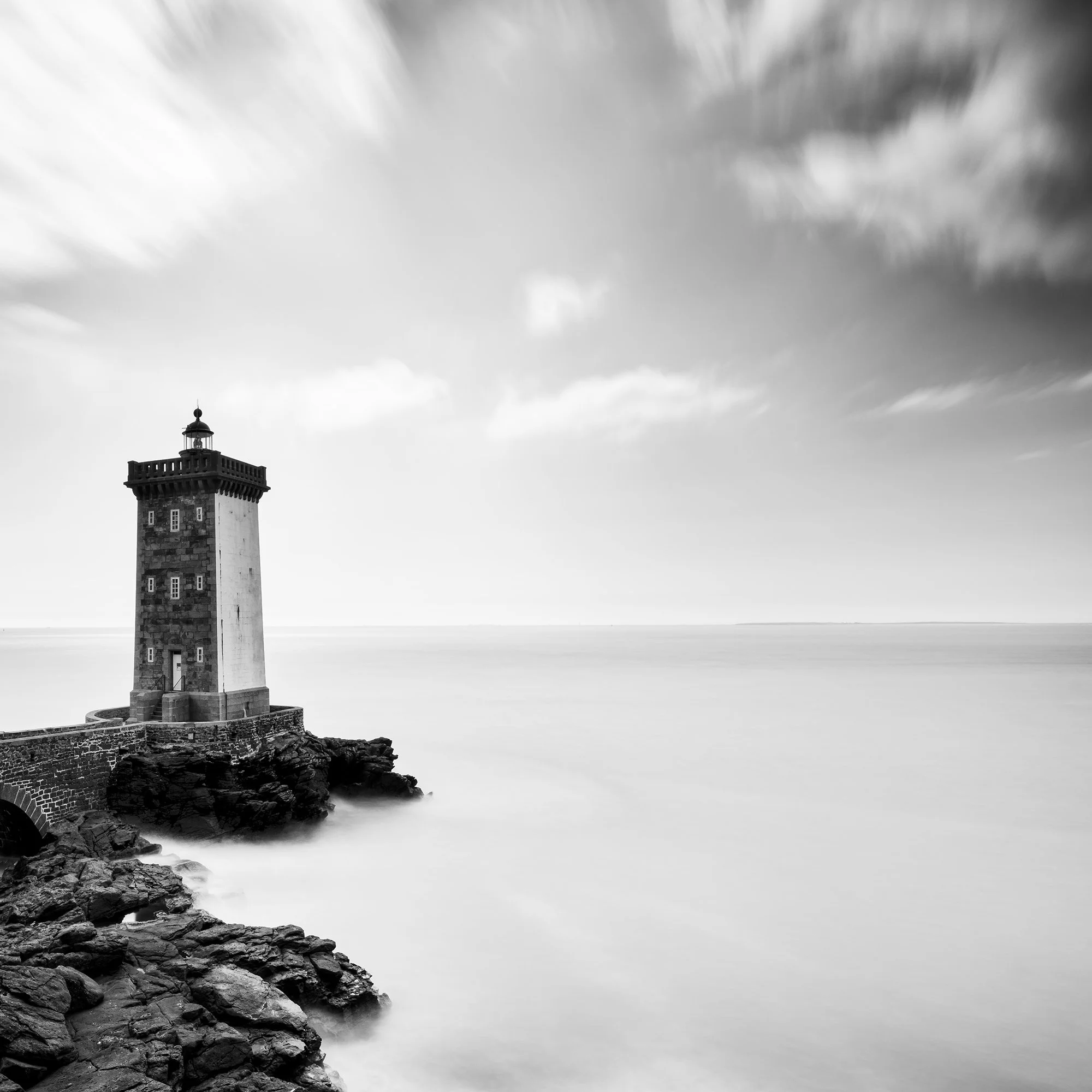 Black-and-white coastal lighthouse with stone bridge across rocks and overcast sky, Detail 2