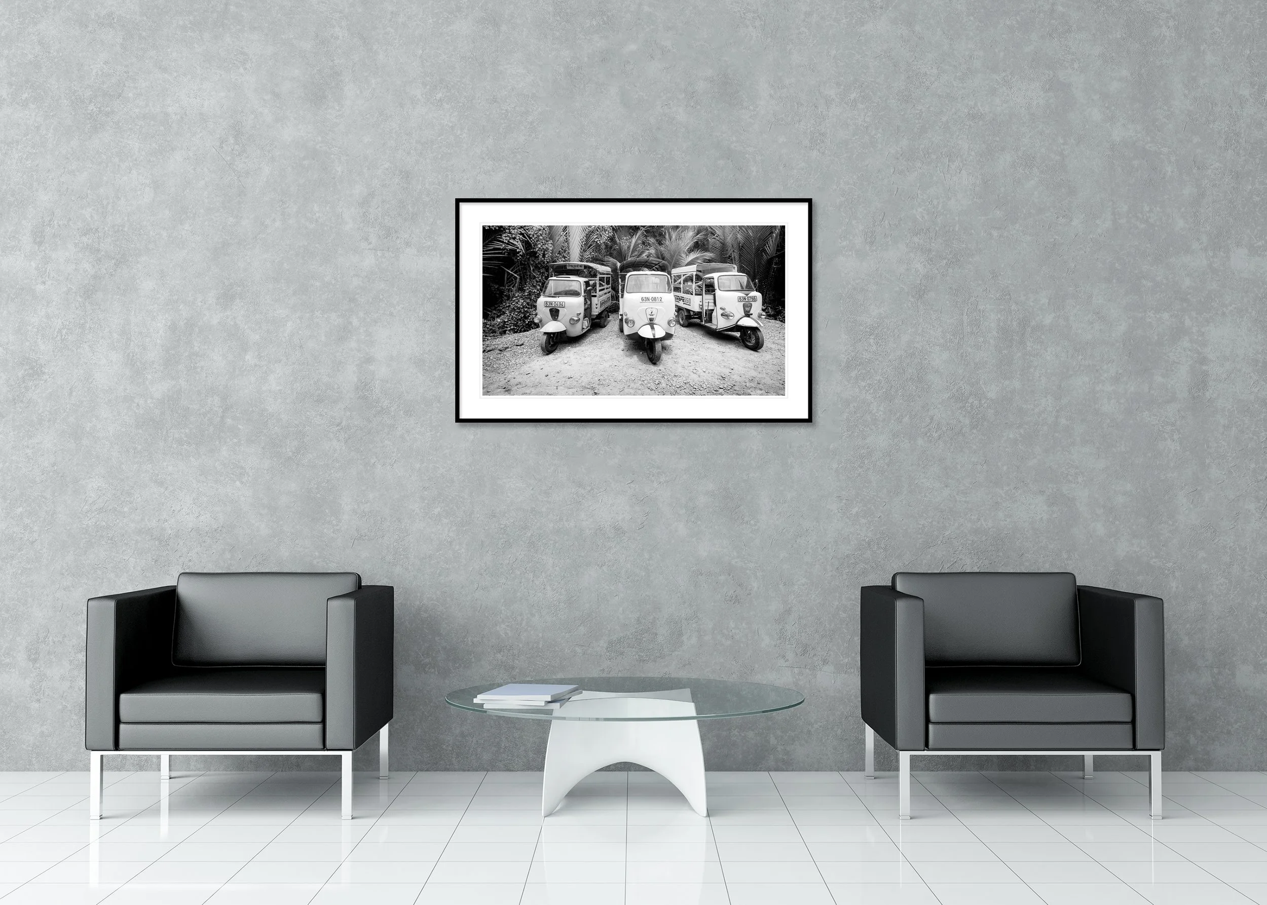 Monochrome image of three tuk-tuks parked side by side on a gravel path amid dense tropical foliage, archival pigment print in a classic frame with mount.
