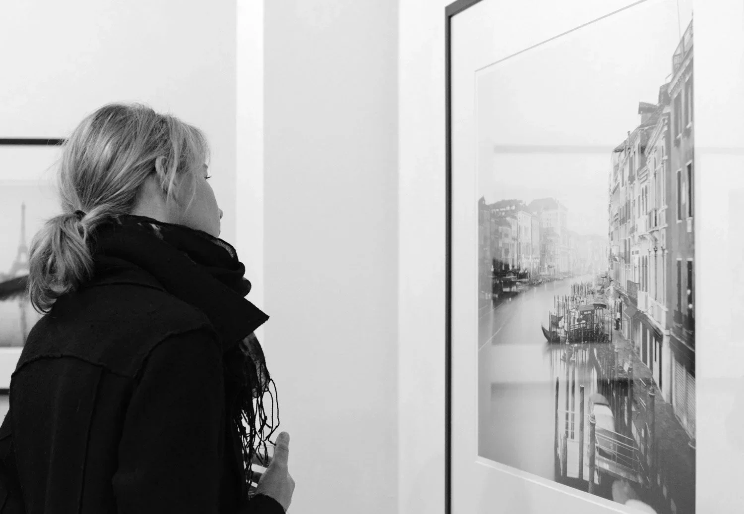 Visitor studying a framed black-and-white Venice canal photograph by Gerald Berghammer at ESSENTIAL LIGHT 2018, Galerie STP in Greifswald.