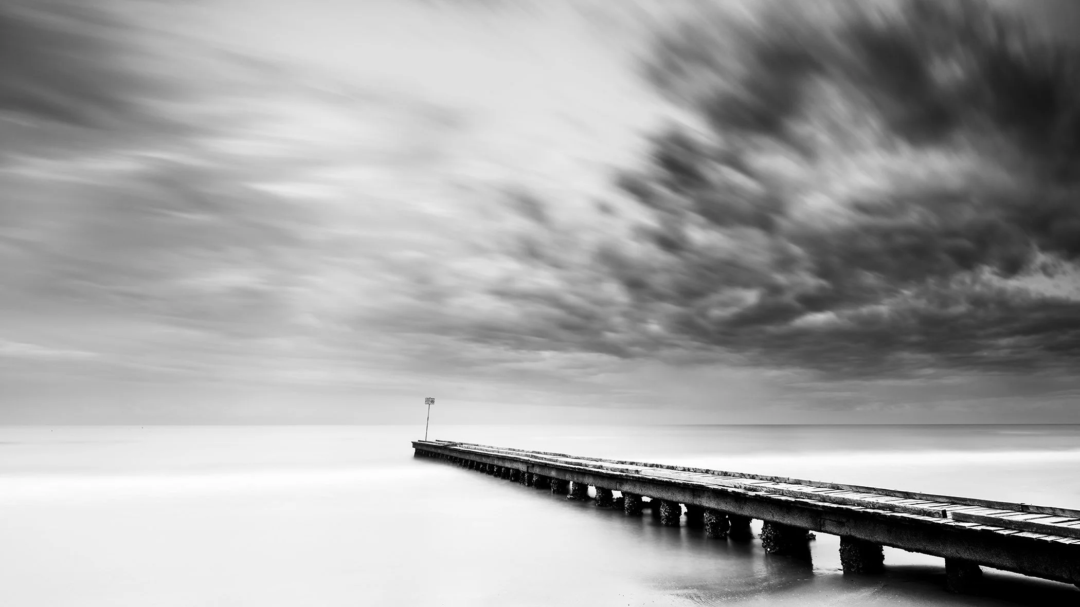 Stormy Adriatic Sea Panorama by Gerald Berghammer, minimalist black-and-white long-exposure photograph of a pier on the Adriatic coast of Italy.