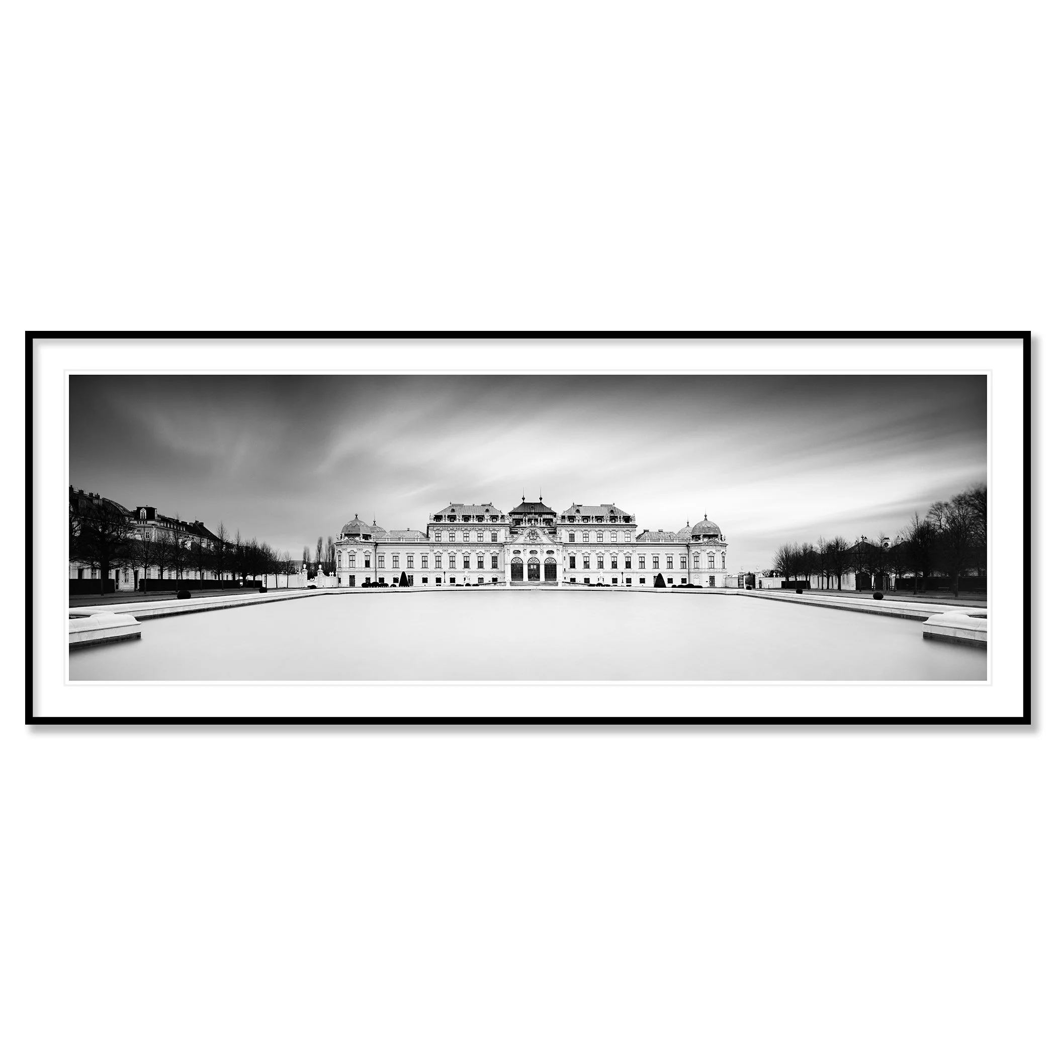 Gerald Berghammer - Black and white photo. Historic building with classical architecture, surrounded by a large open courtyard with water basin and trees. Classic framed black