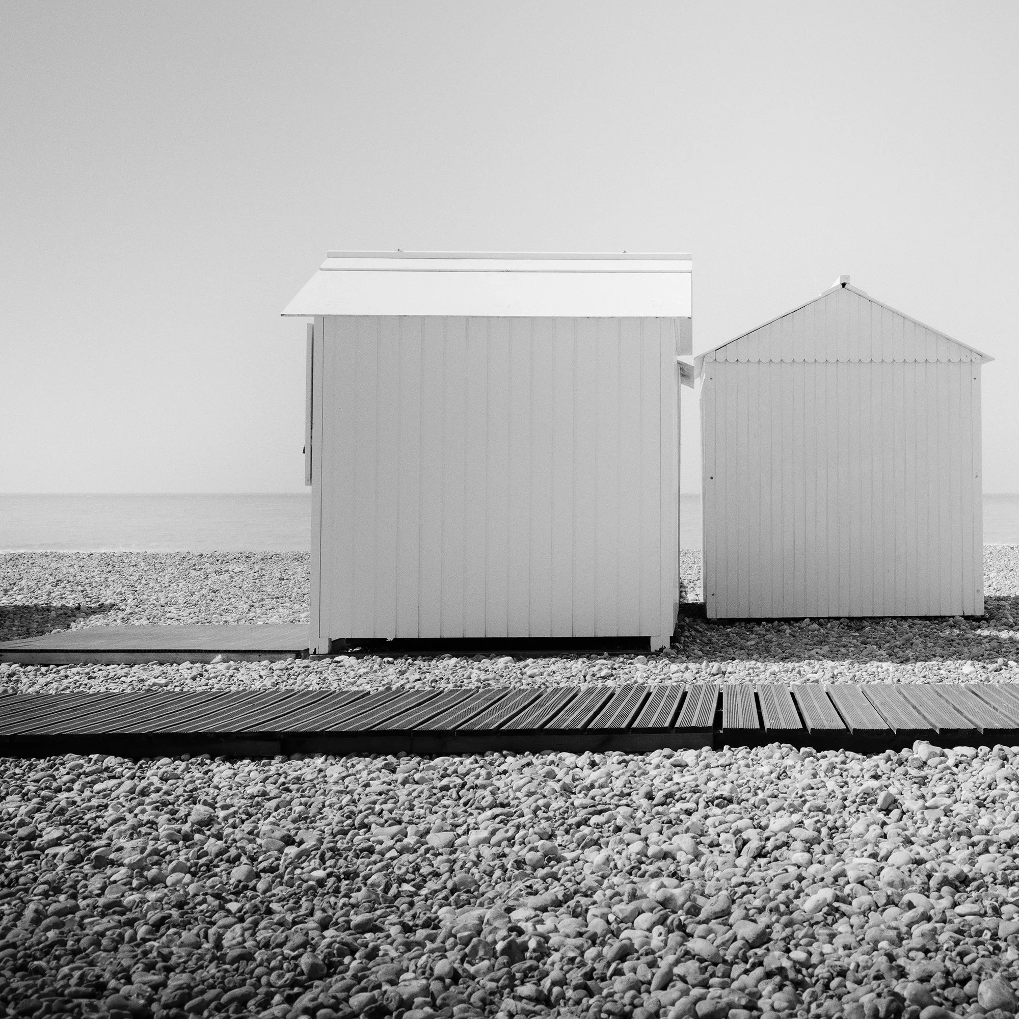 Close-up detail of Esplanade Study 2 by Gerald Berghammer showing the minimalist beach huts and pebble shore in France.