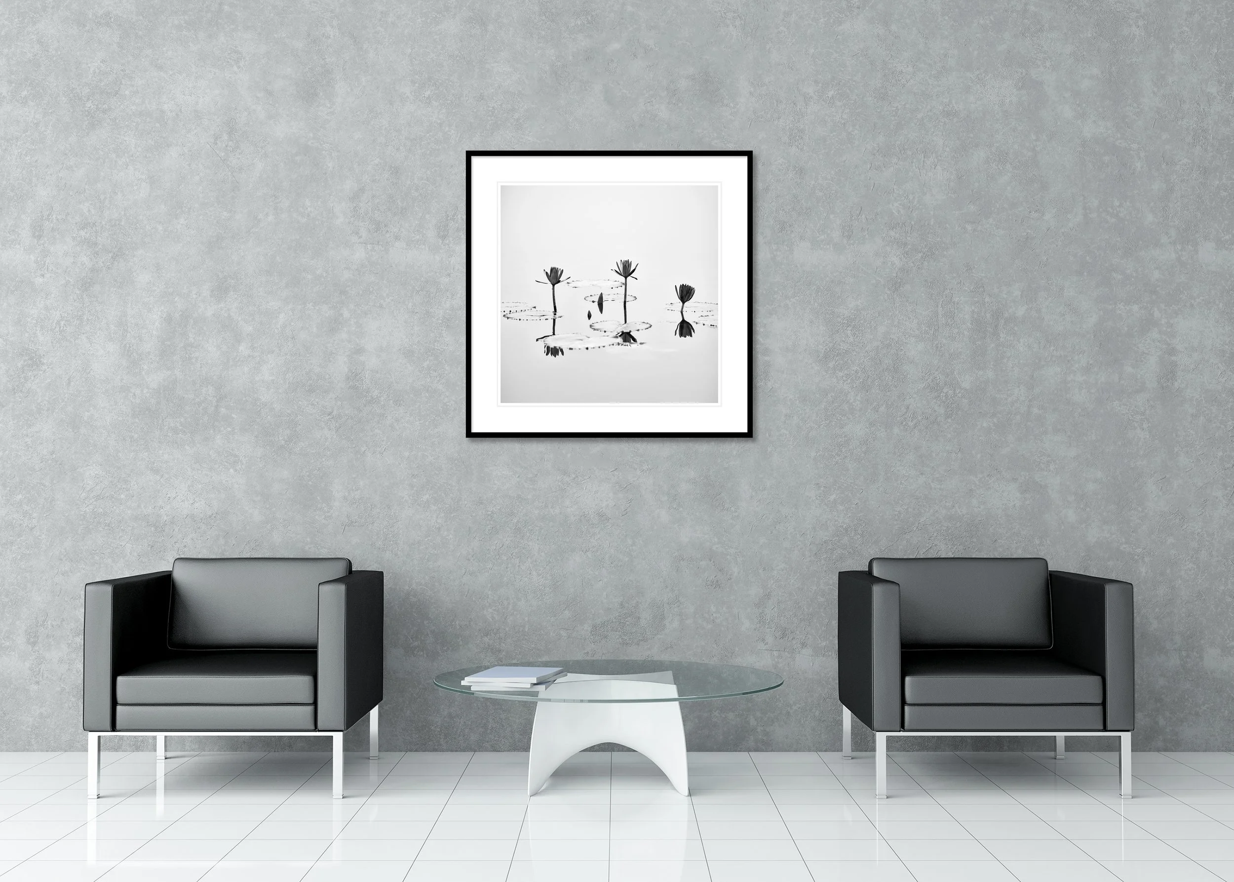 Black-and-white photograph of lotus flowers rising above still water with soft reflections in a calm, minimalist composition, archival pigment print in a classic frame with passe-partout.
