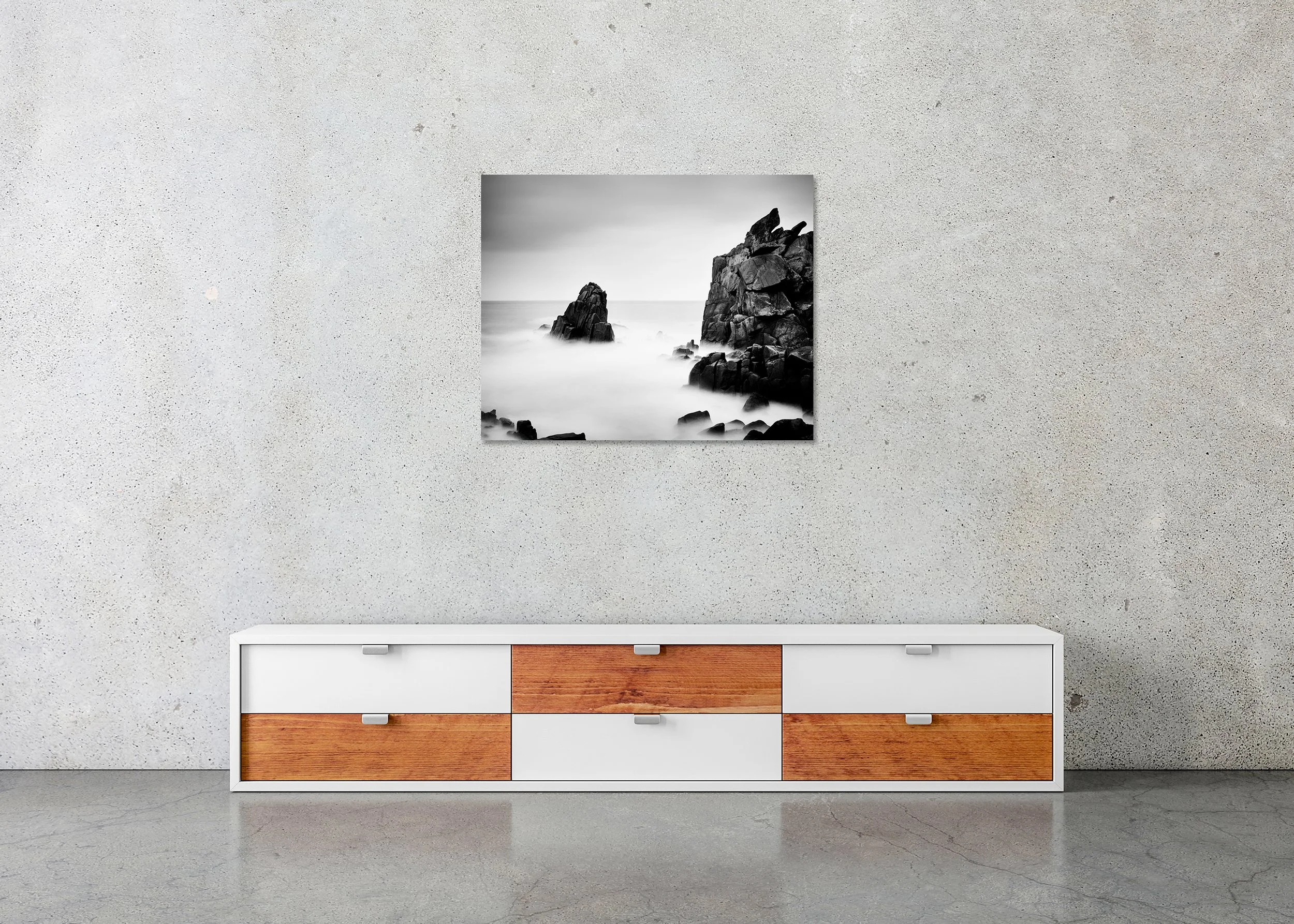 Black-and-white long-exposure seascape photo print mounted to Dibond, frameless, showing rugged coastal rocks rising from a misty sea