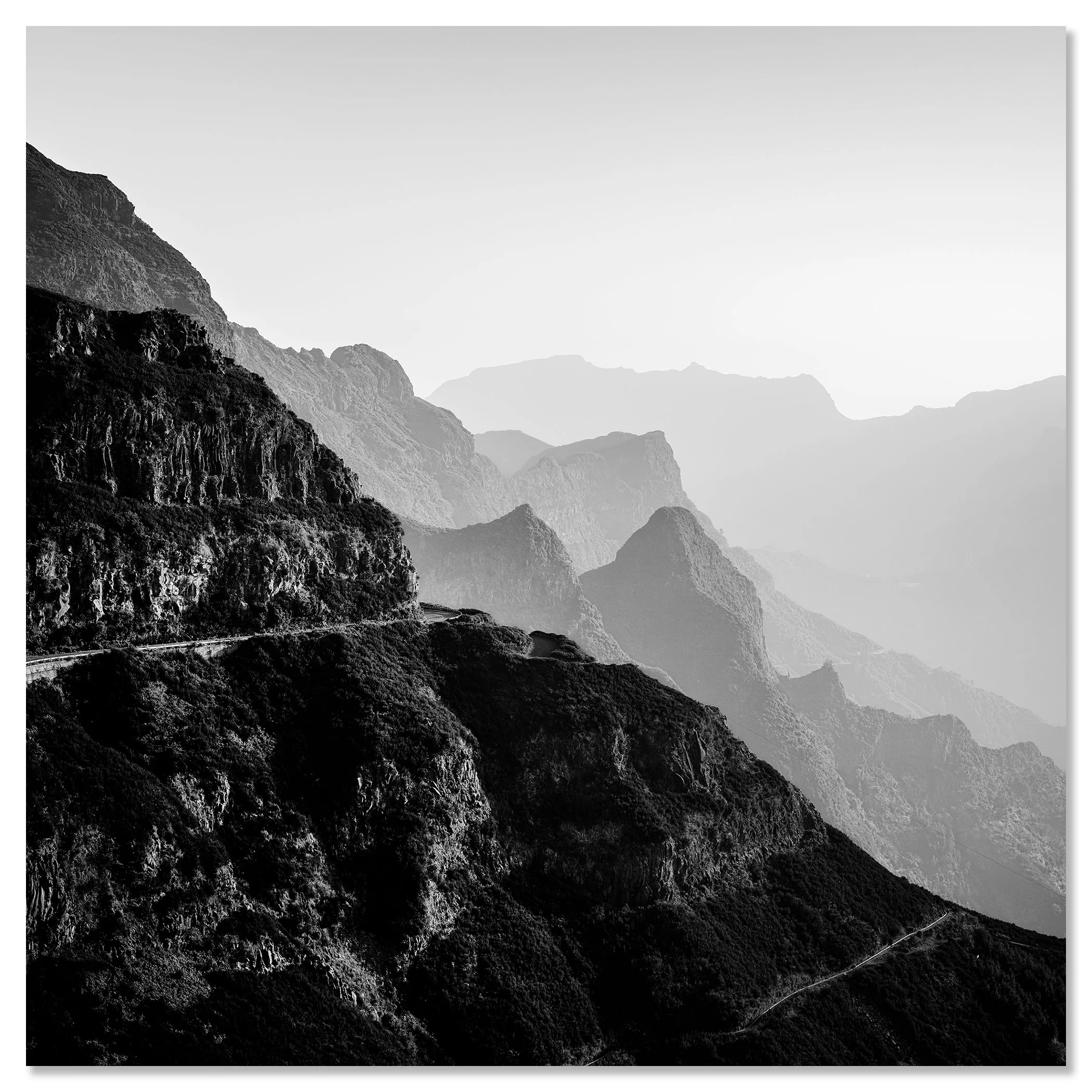 Black and white mountain landscape with rugged cliffs and a winding road in the haze – dibond frameless