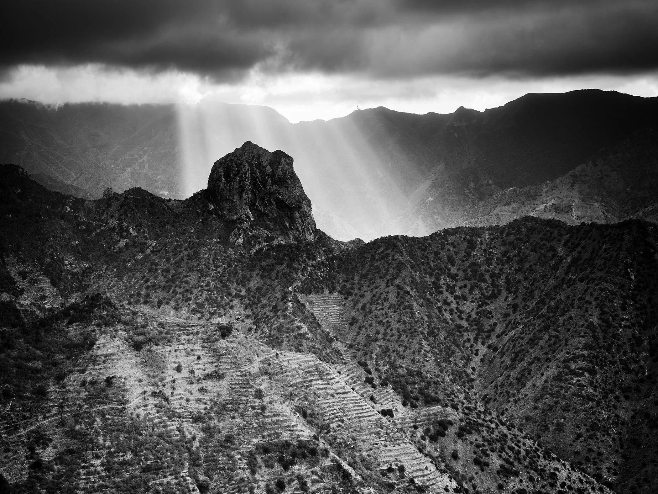 Here Comes the Sun Study 1, black-and-white mountain landscape with dramatic sunbeams over La Gomera, Spain. Photo by Gerald Berghammer.