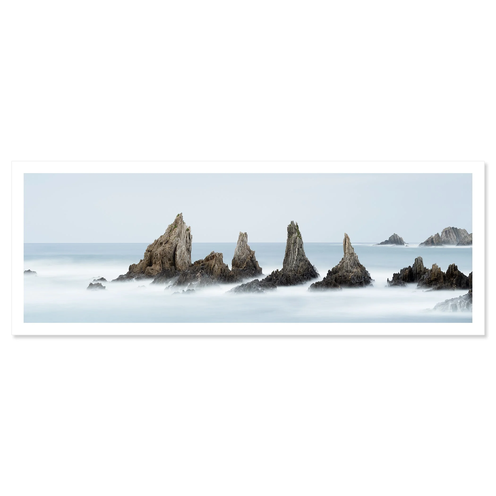 © 2023 Gerald Berghammer - Color seascape. Long exposure photograph of jagged sea stacks rising from the ocean with misty water and a light sky in the background. Fine art print only