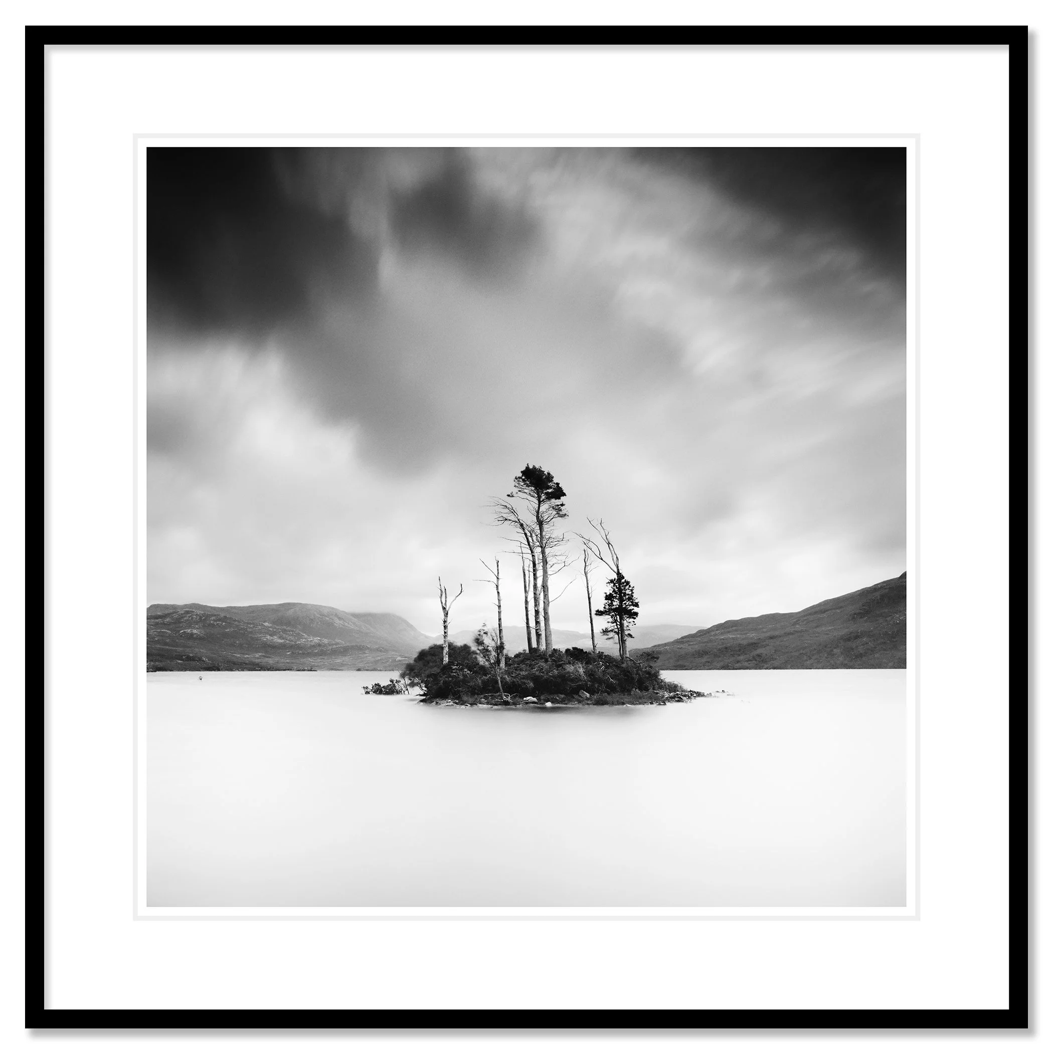 © 2012 Gerald Berghammer - Black and white waterscape photography. Small island with tall, thin trees surrounded by water and distant mountains under a cloudy sky. Classic framed black